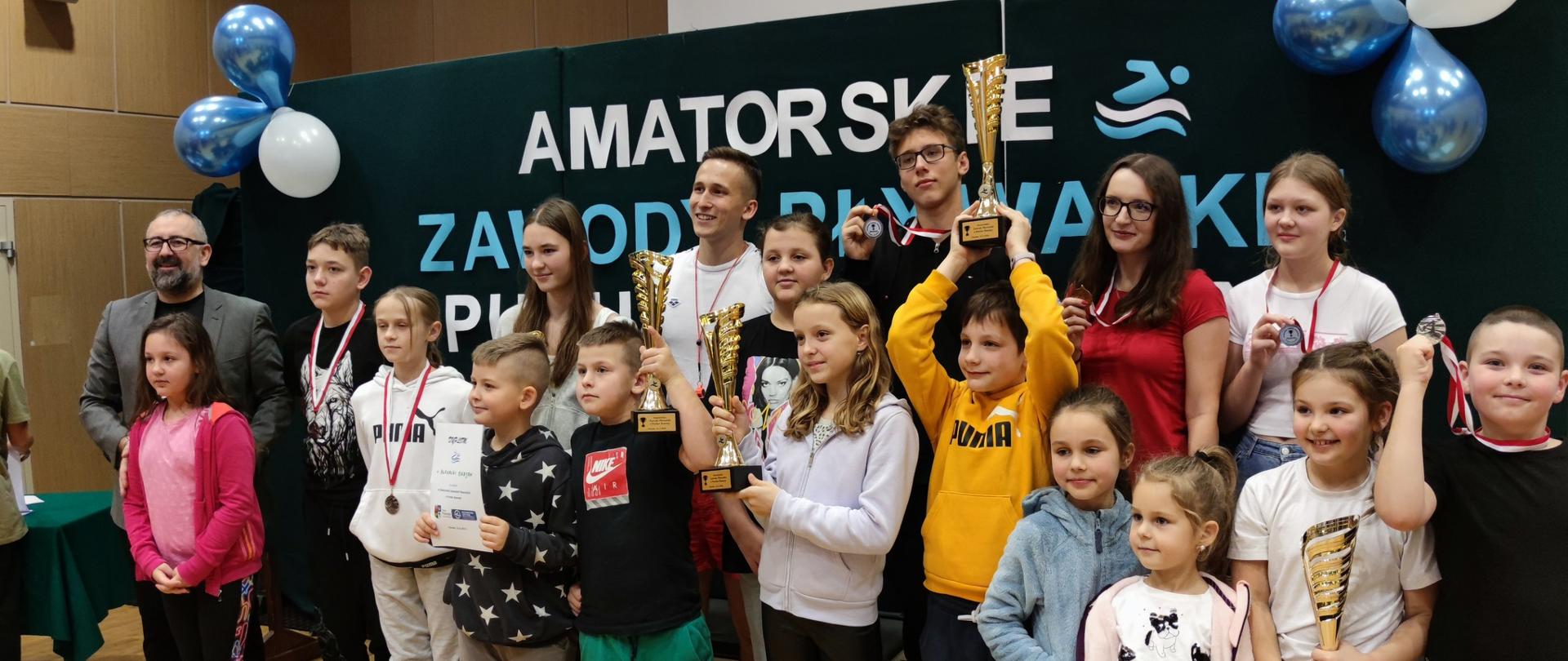 Zdjęcie grupowe dzieci i młodzieży biorących udział w zawodach pływackich oraz Starosty Przasnyskiego Krzysztofa Bieńkowskiego.