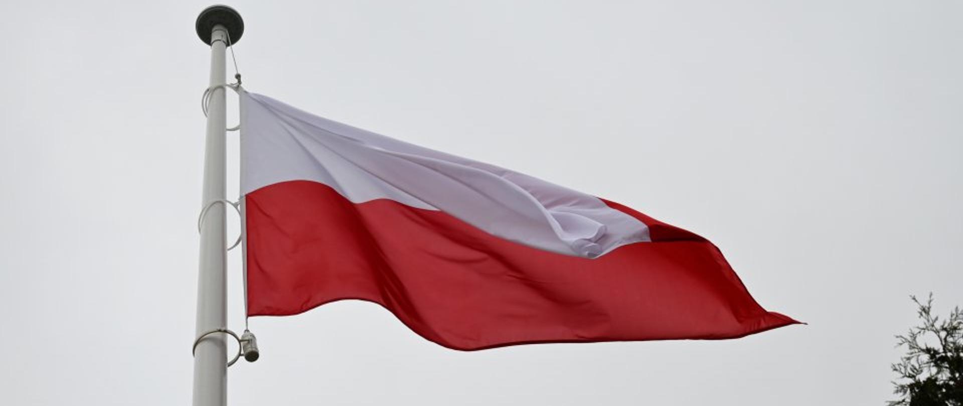 Na zdjęciu widzimy powiewającą na wietrze flagę Polski wiszącą na maszcie