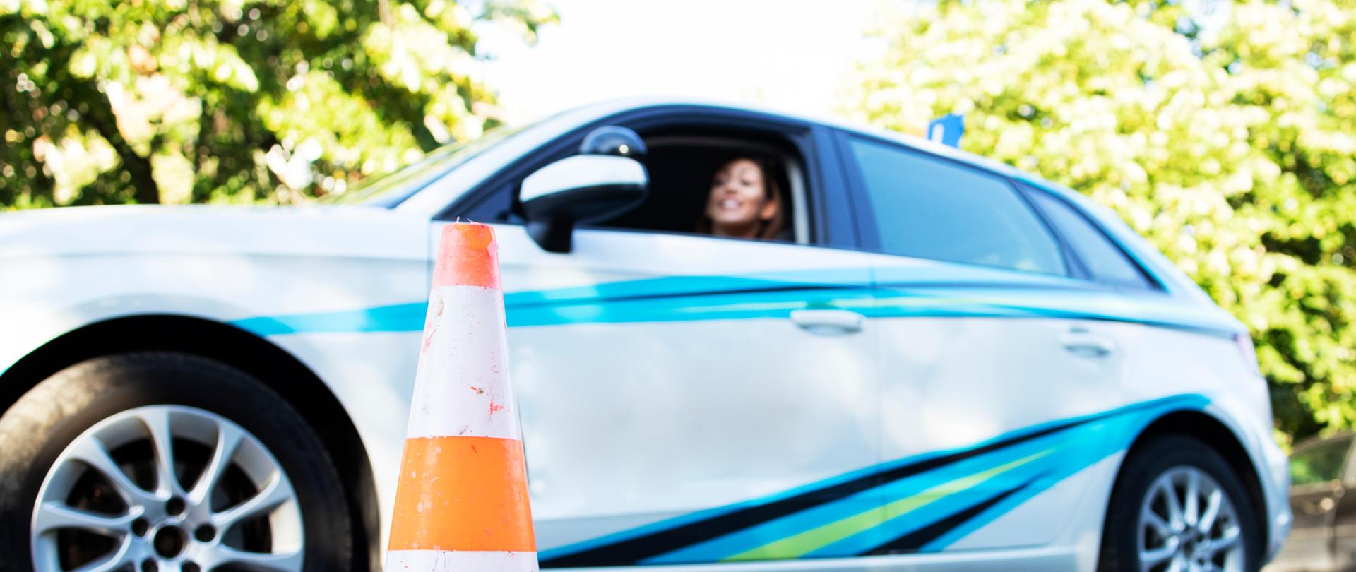 Młoda kobieta siedzi w samochodzie szkolnym gotowy do zajęć nauki jazdy.