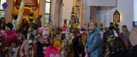Zdjęcie przedstawia uczestników konkursu pozujących do zdjęć z palmami na tle ołtarza w kościele parafialnym w Podsarniu