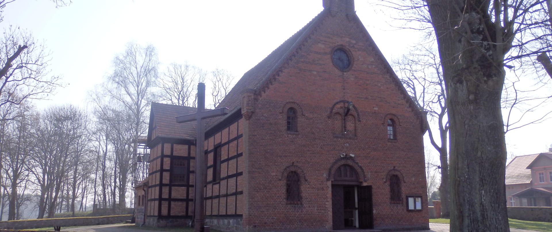 kościół z czerwonej cegły i spadzistym dachem otoczony kamiennym murem