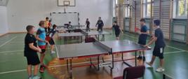 Młodzież przy stole tenisowym rozgrywa mecz w parach