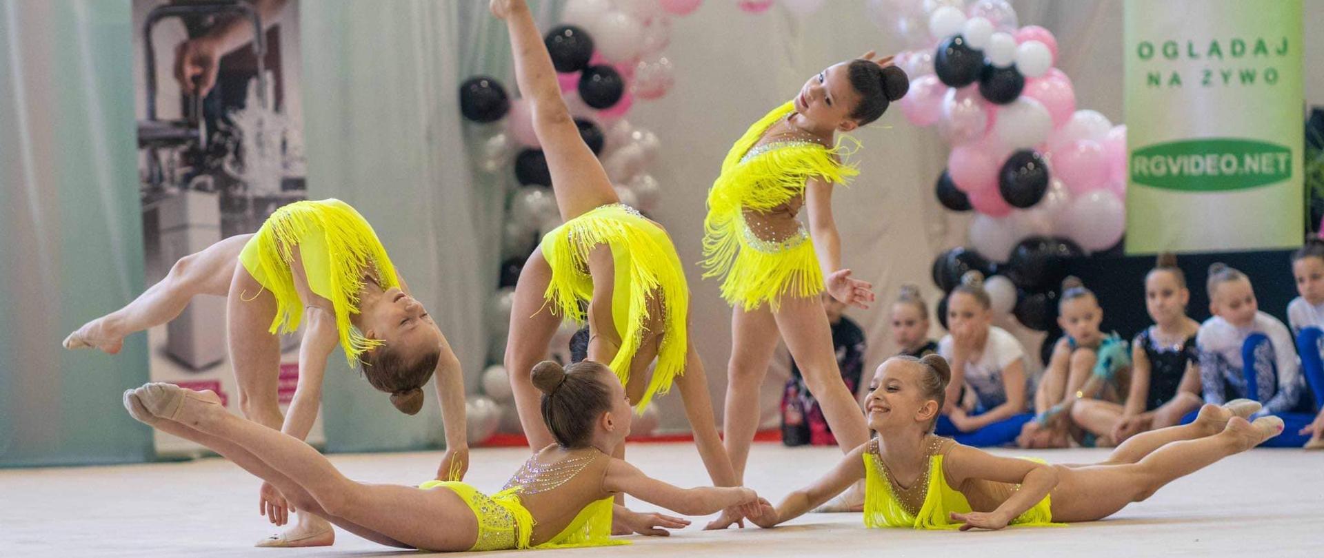 5 dziewczynek w żółtych strojach zapozowało w trakcie pokazu gimnastyki artystycznej
