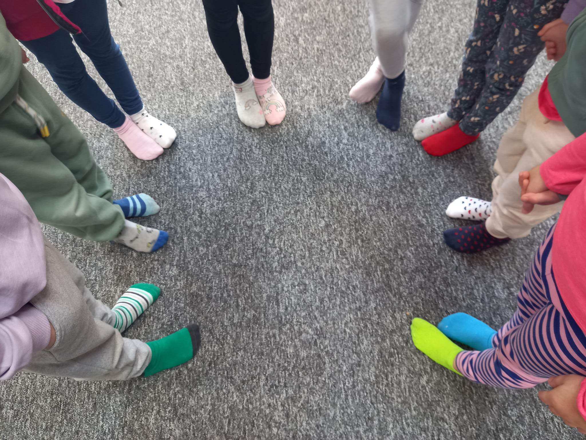 Dzieci stojące w okręgu z kolorowymi skarpetkami nie do pary