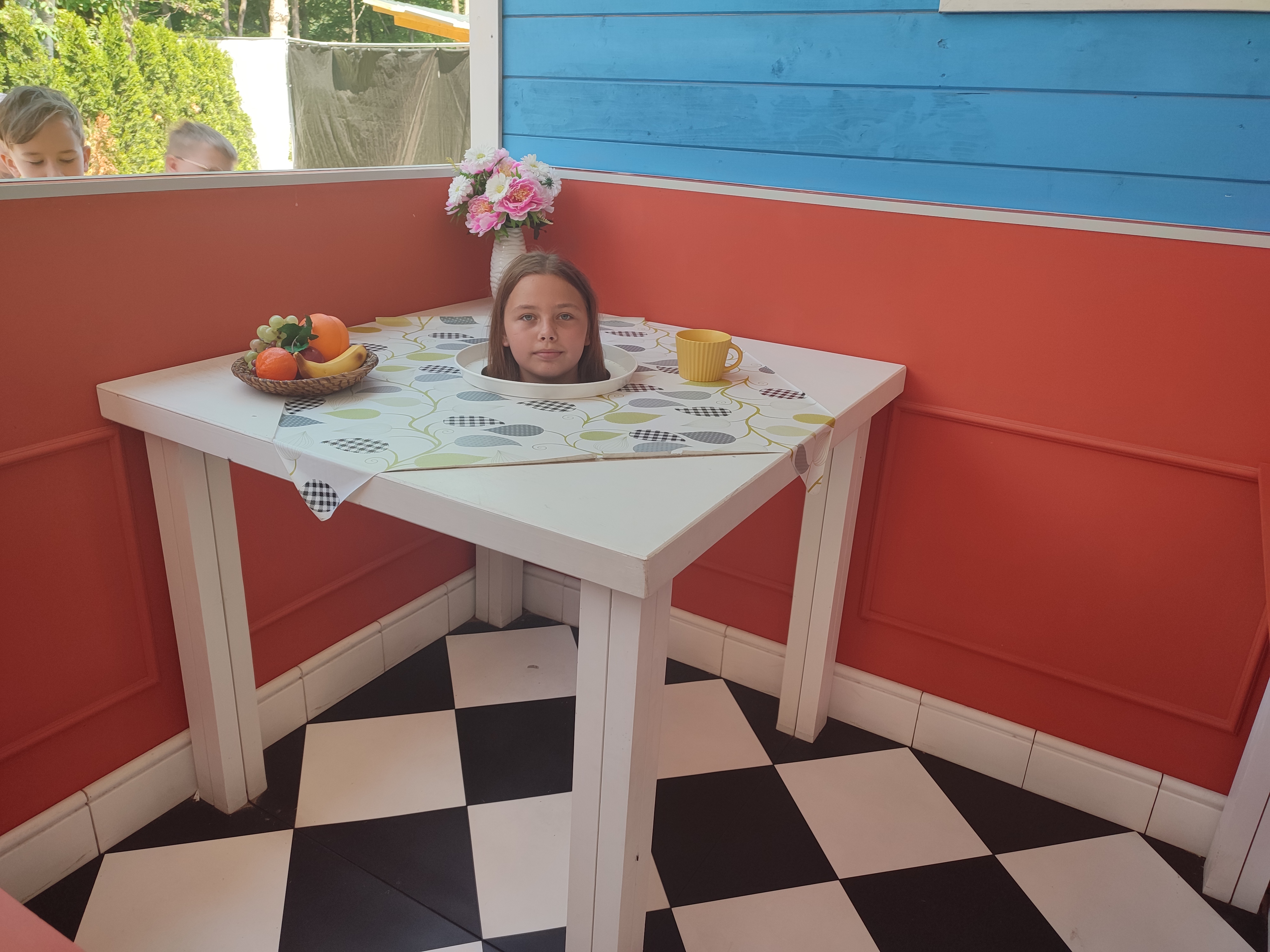 Zdjęcie przedstawia dziecko pozujące w niewidzialnym stoliku w Farmie Iluzji.