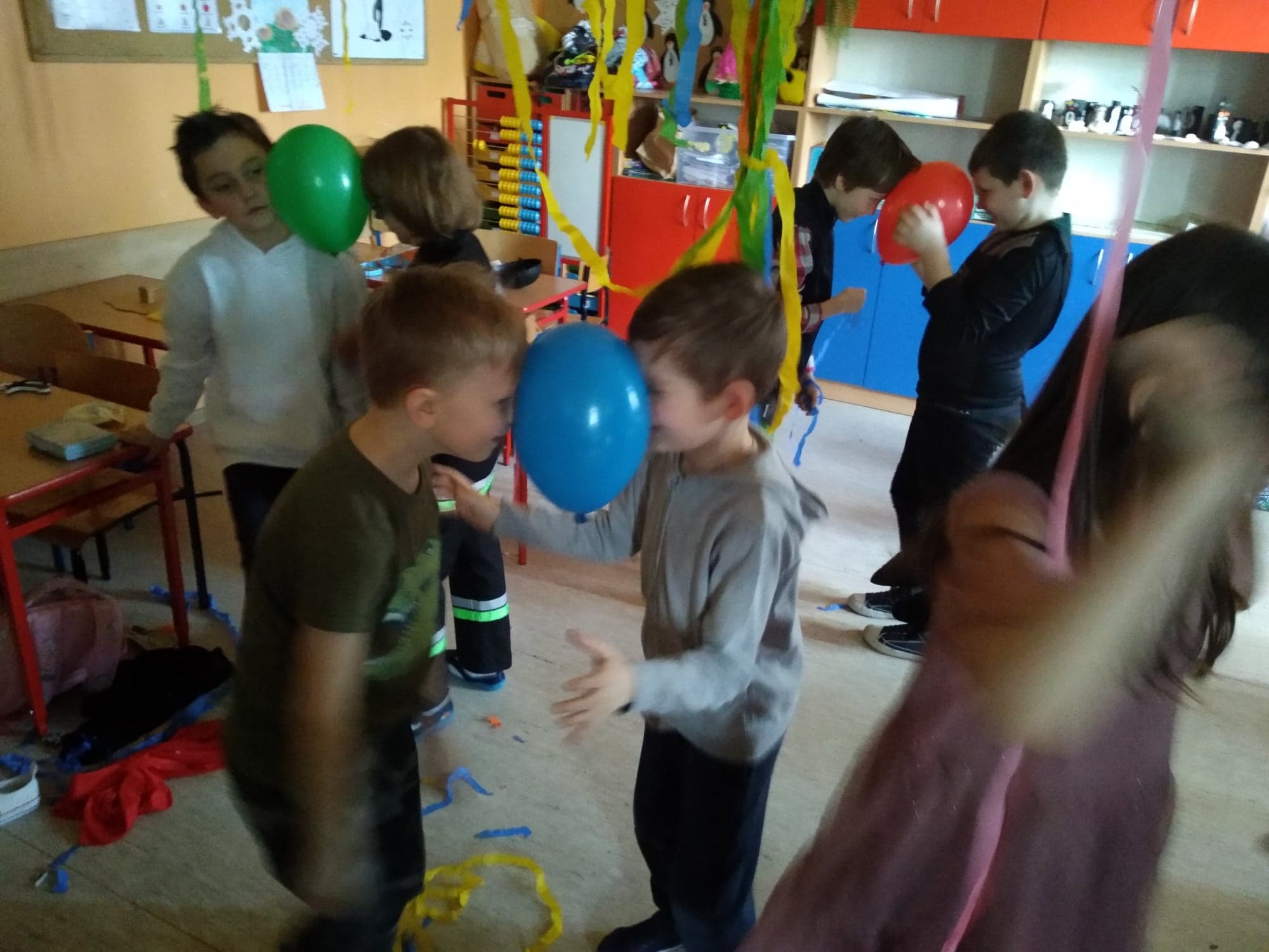 Chłopcy trzymają balon głowami