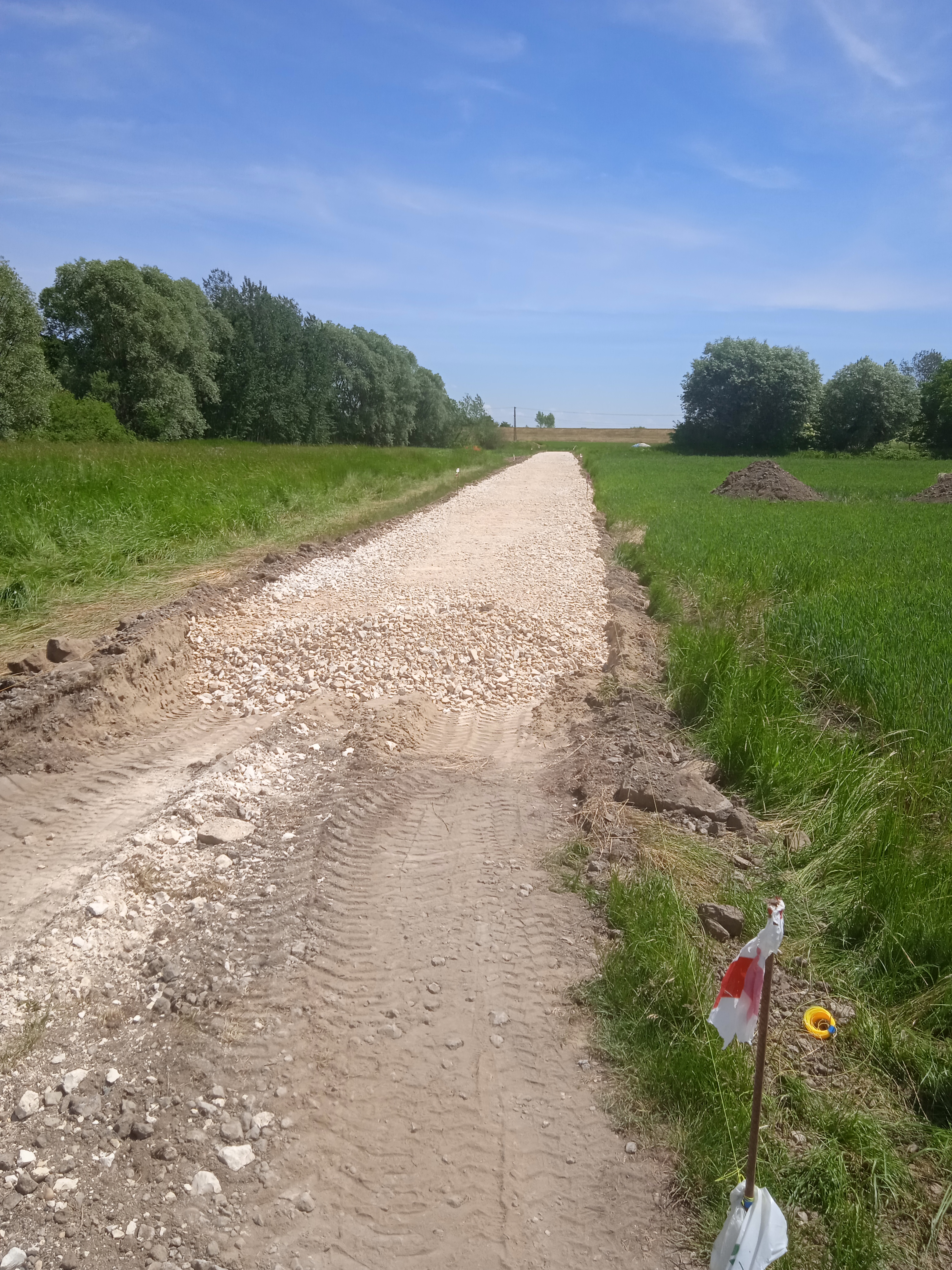 zdjęcie przedstawia drogę polną w miejscowości Wola Rogowska w trakcie modernizacji, częściowo utwardzoną kamieniem.