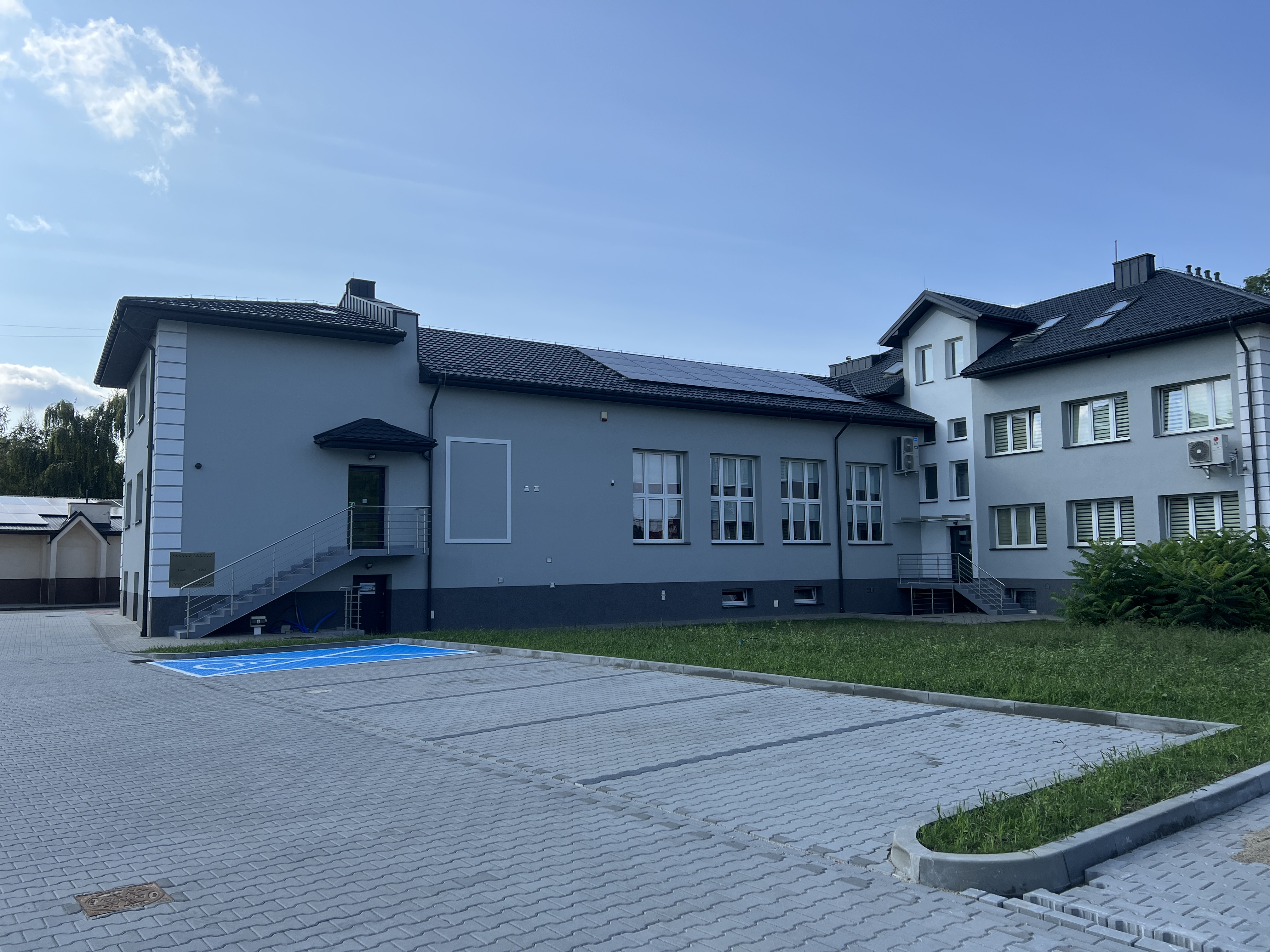 zdjęcie przedstawia fragment parkingu zbudowanego z kostki brukowej znajdującego się za budynkiem Urzędu gminy w Wietrzychowicach