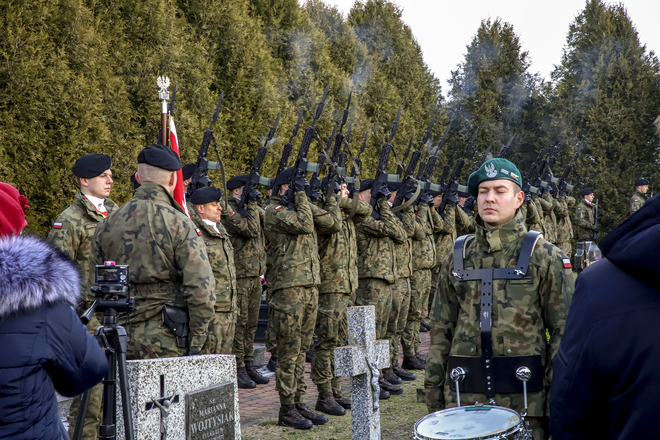 Na zdjęciu salwa honorowa żołnierzy z 19. Lubelskiej Brygady Zmechanizowanej podczas uroczystości na cmentarzu. Żołnierze trzymają uniesione w górę karabiny, z których unosi się dym po wystrzale.