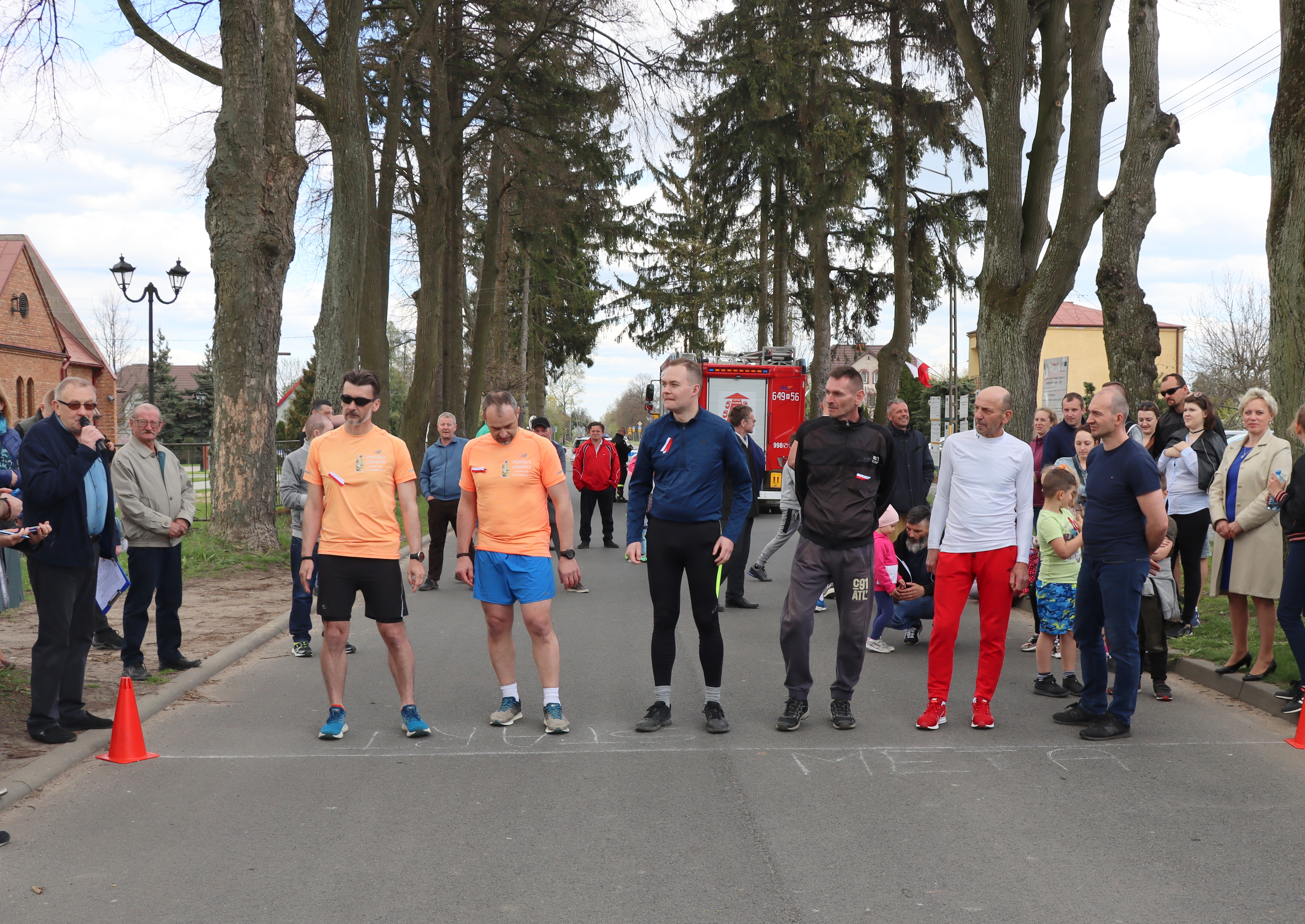 Najstarsza grupa wiekowa mężczyzn (6 osób)uczestnicząca w Biegu na mecie startu. Kibicuje im kolorowy tłum zgromadzony wzdłuż trasy biegu.