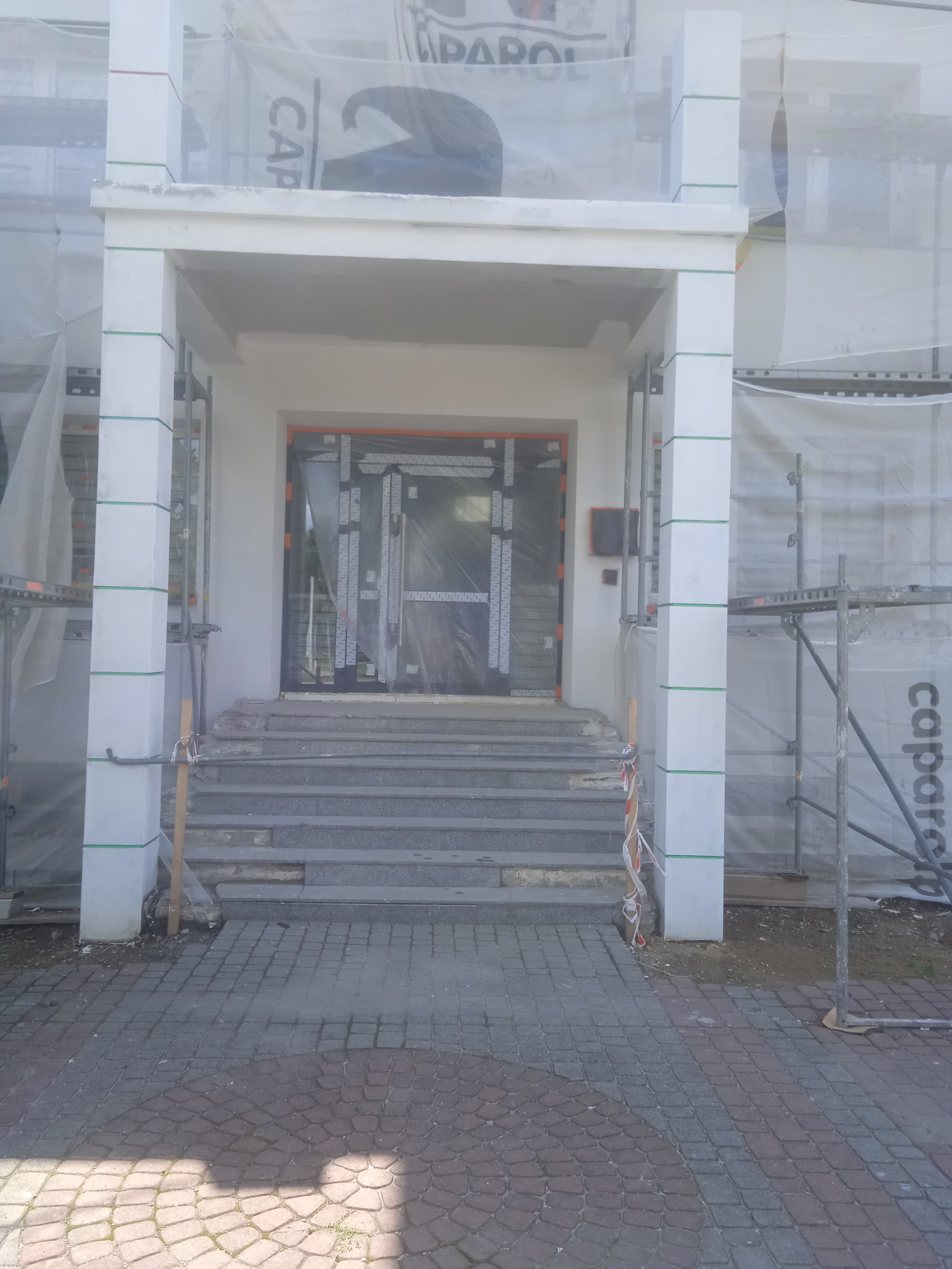 Zdjęcie przedstawia postęp prac przy ocieplaniu budynku urzędu- widok na wejście główne do budynku.