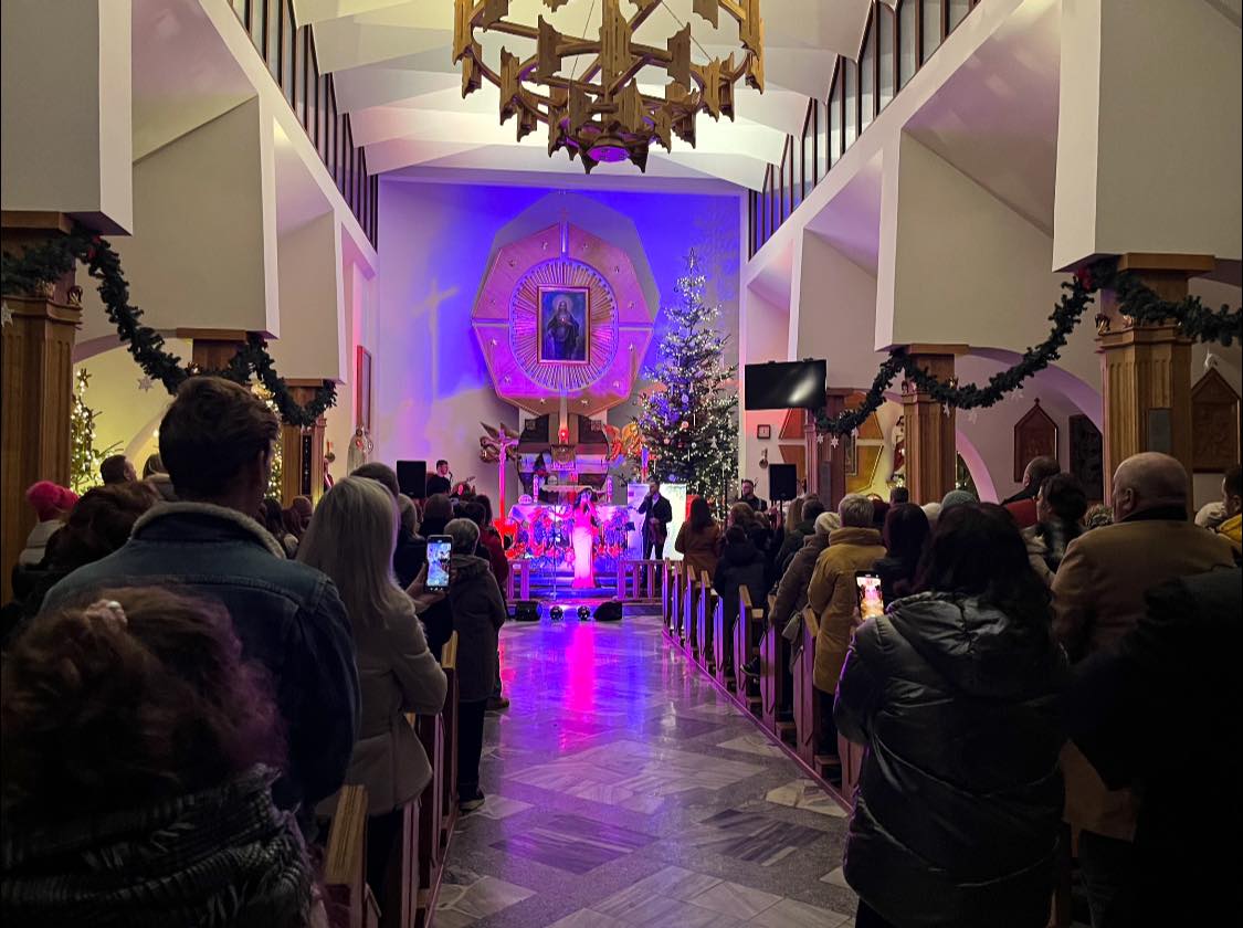 Koncert Bożonarodzeniowy w Sieniawie przedstawiający w tle artystów oraz przybyłych gości