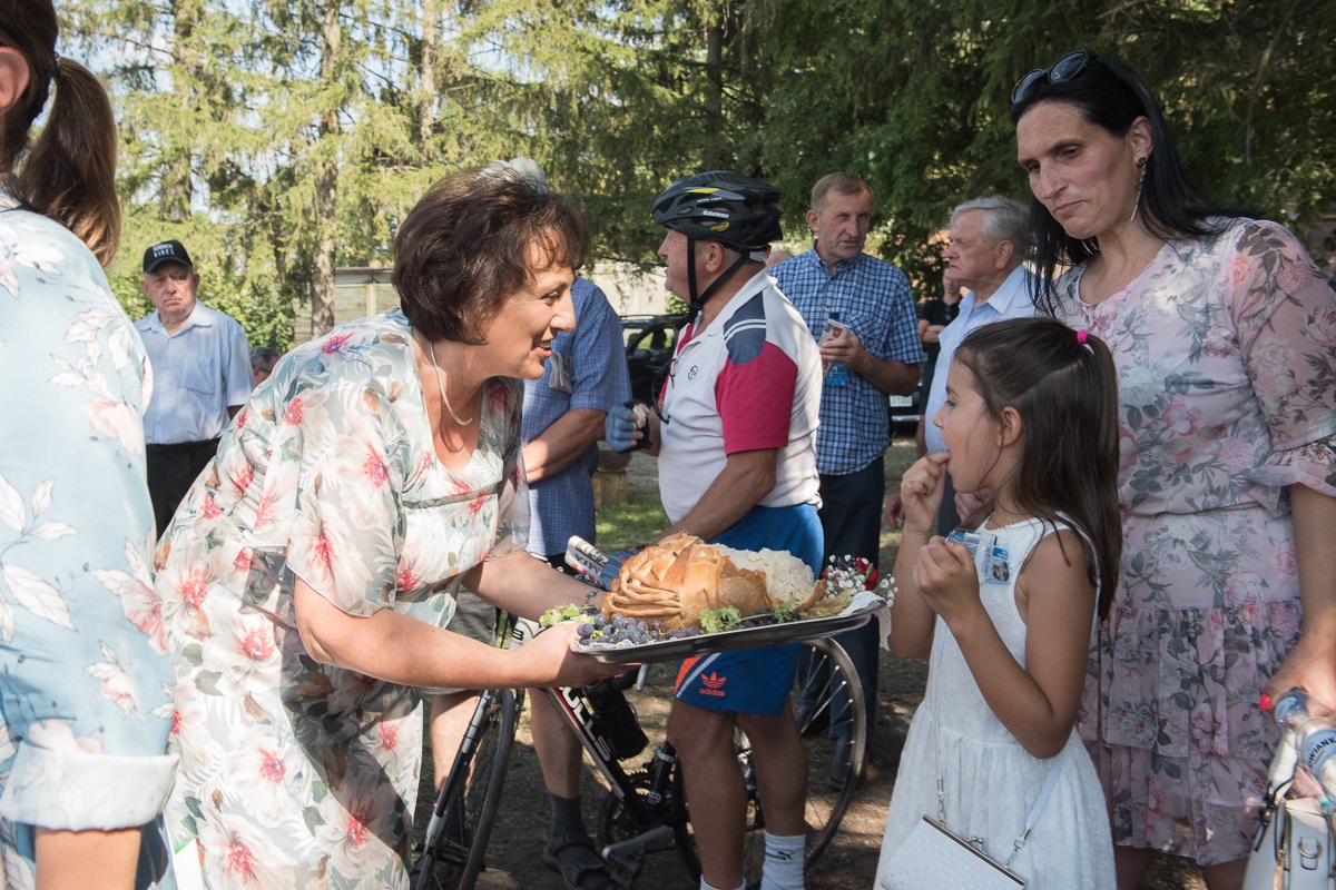Starosta Elżbieta Sadowska częstuje chlebem dziewczynkę oraz jej mamę.