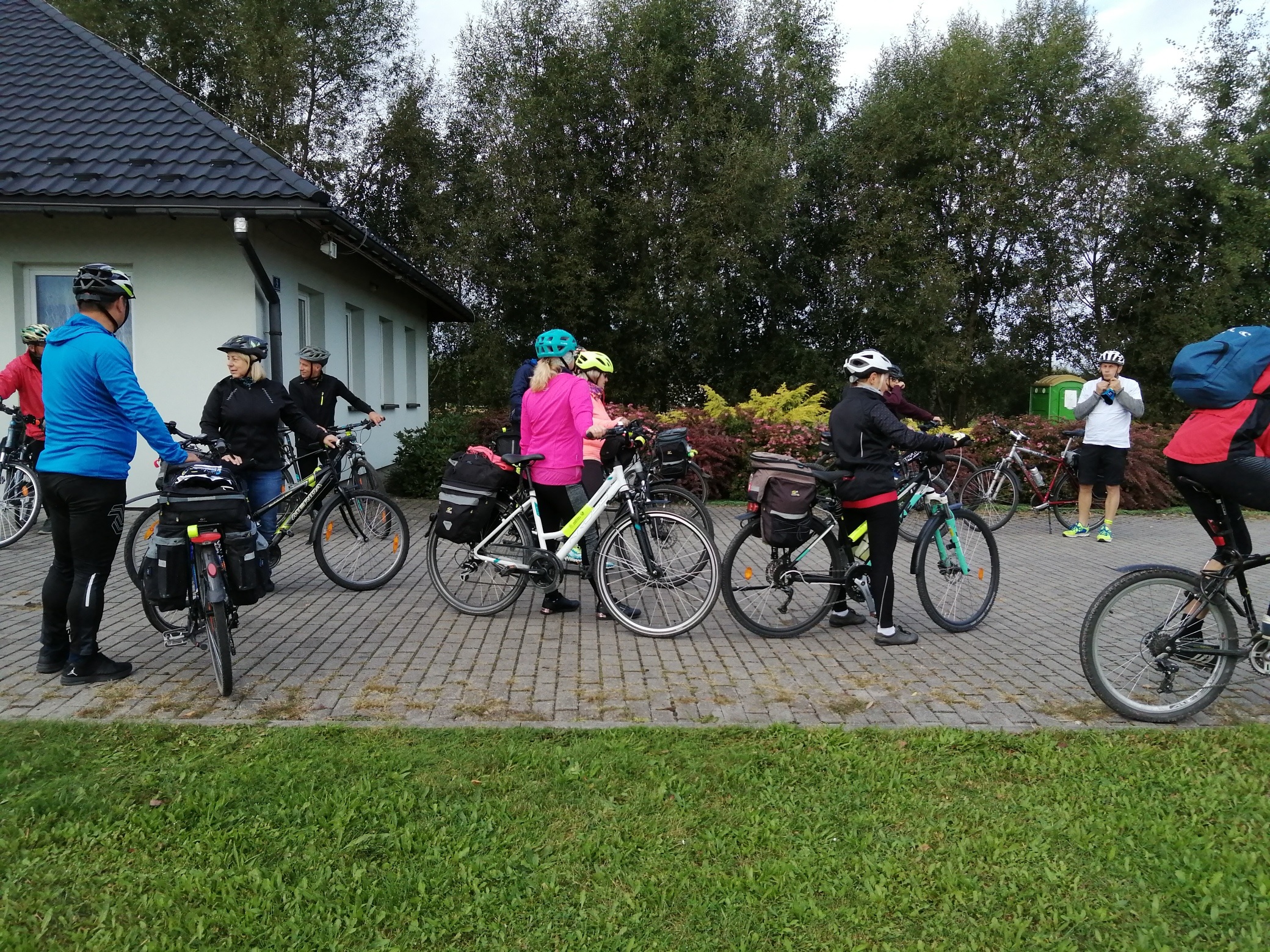 Rajd Rowerowy z Brzezówki do Łomnej Górnej. Jego uczestnicy stoją przy swoich rowerach przed Domem Wiejskim w Brzezówce