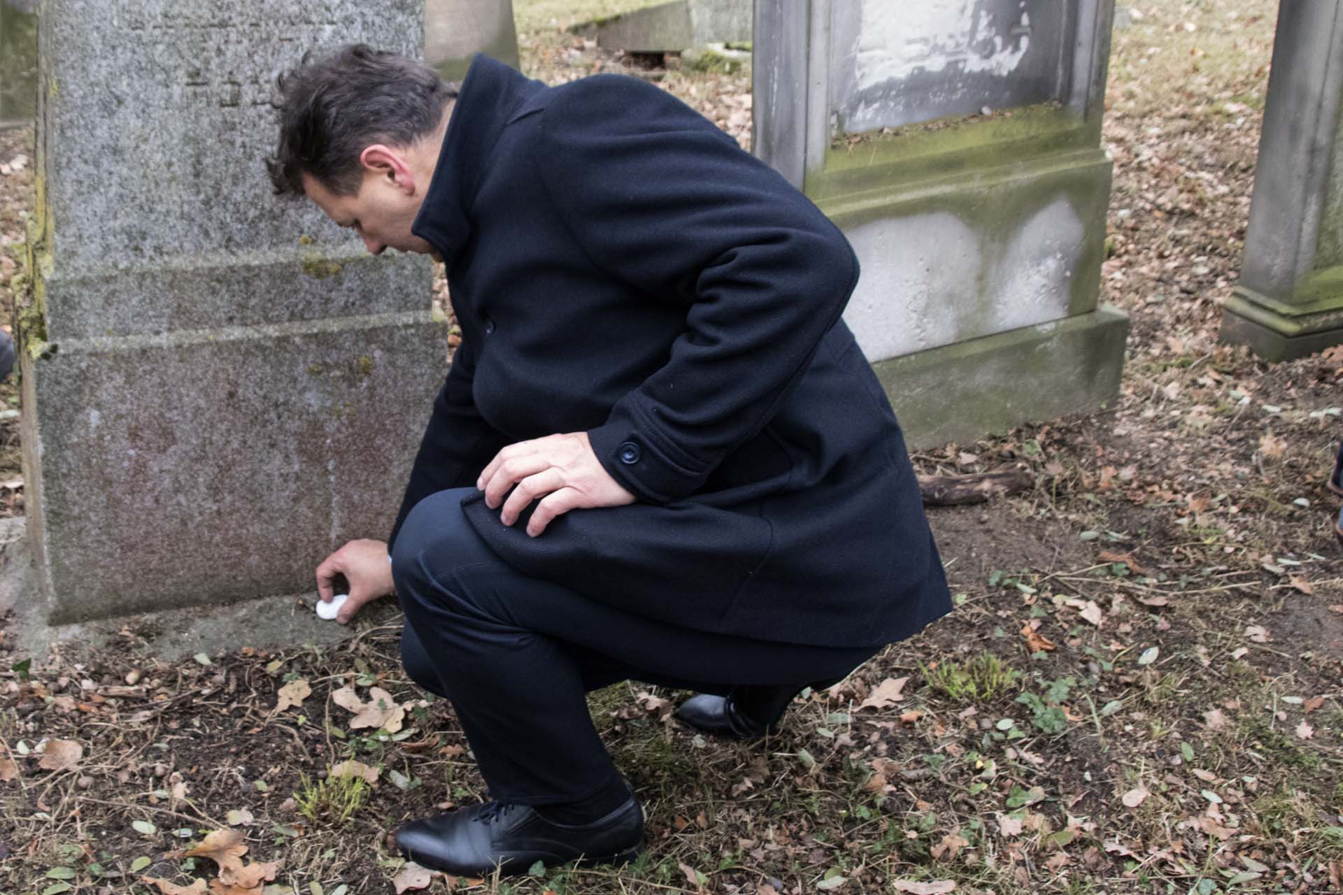 Złożenie kamyków na grobach na cmentarzu żydowskim w Oleśnie - na zdjęciu Starosta Oleski Roland Fabianek