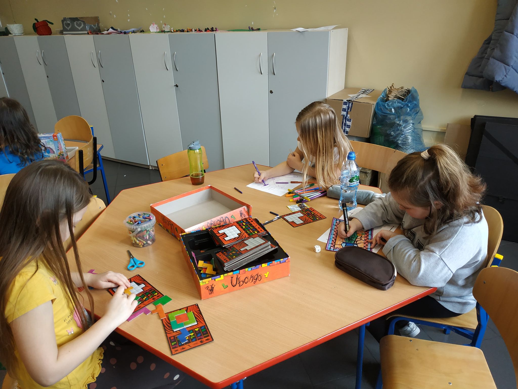 Dziewczynki siedzą przy stoliku i piszą 