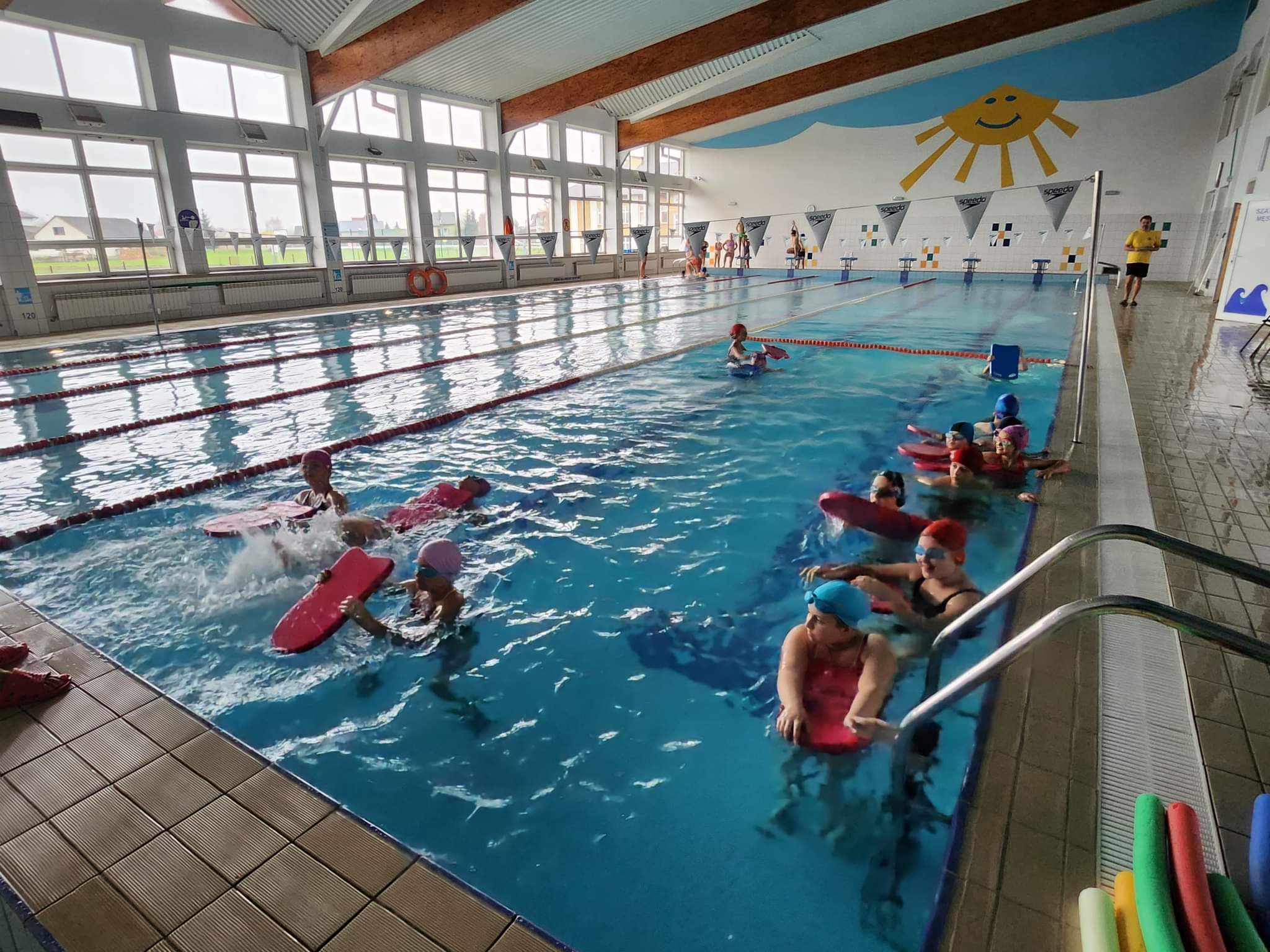 zdjęcie przedstawia uczniów w wieku szkolnym w basenie w trakcie nauki pływania