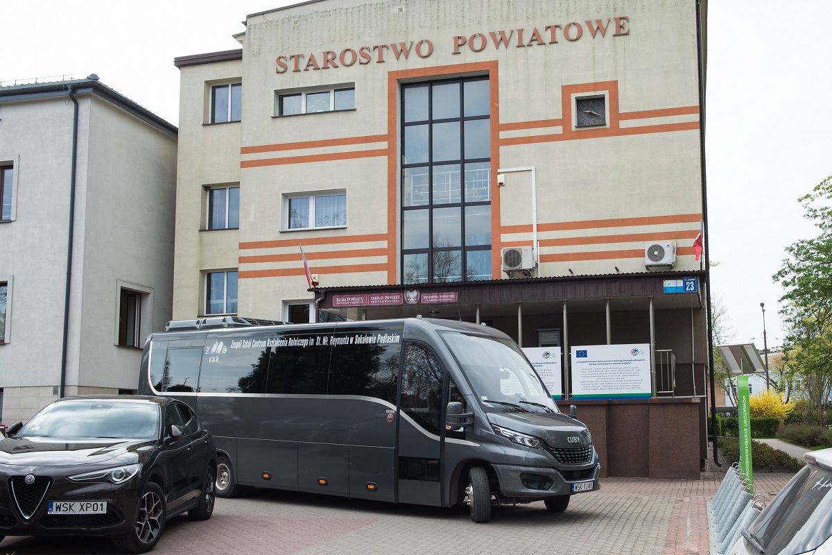 Na zdjęciu szary autobus z napisem Zespół Szkół Centrum Kształcenia Rolniczego w Sokołowie Podlaskim stojący na tle Starostwa Powiatowego w Sokołowie Podlaskim