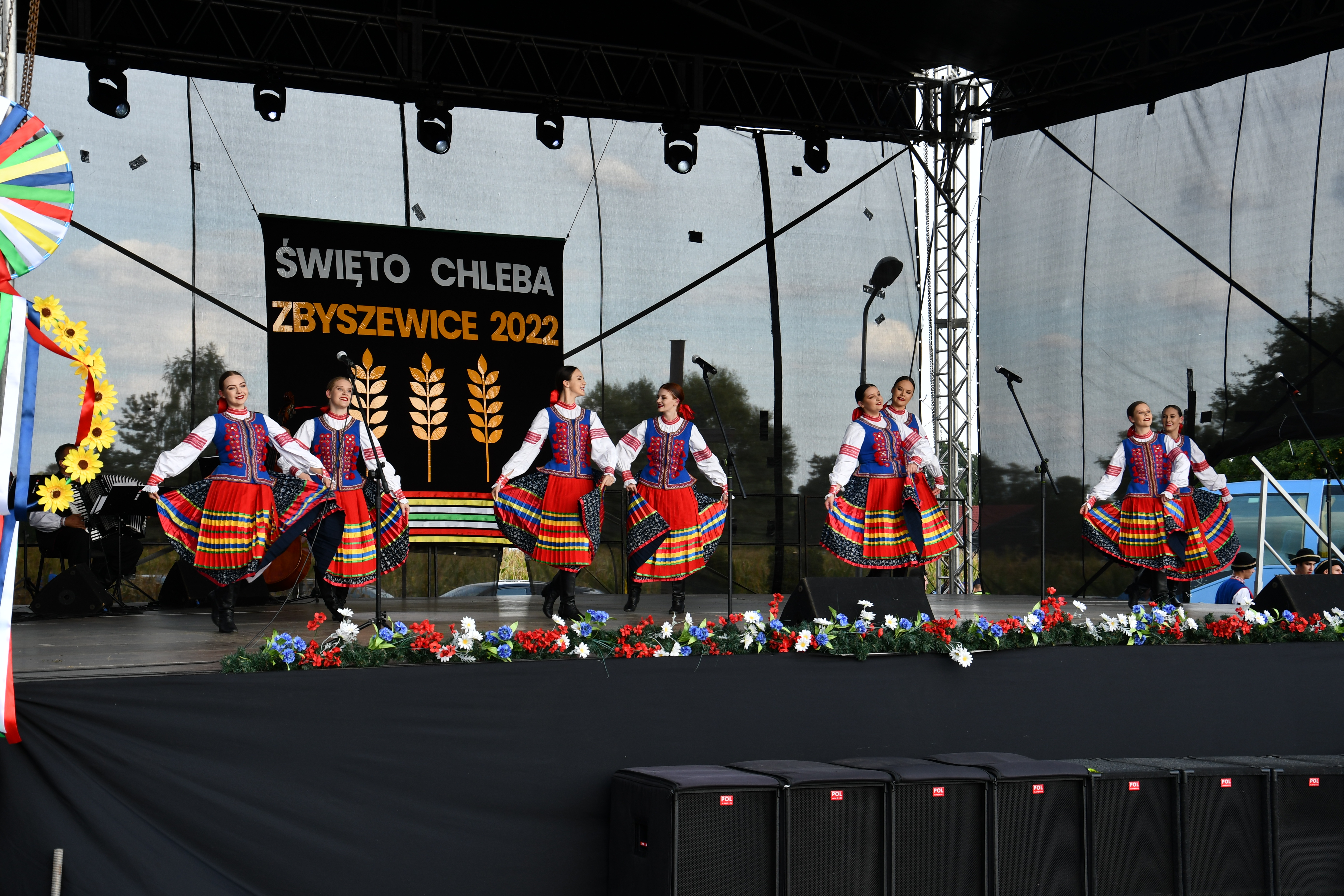 tancerki w strojach ludowych na scenie, w tle napis Święto chleba Zbyszewice 2022 i symbole kłosów