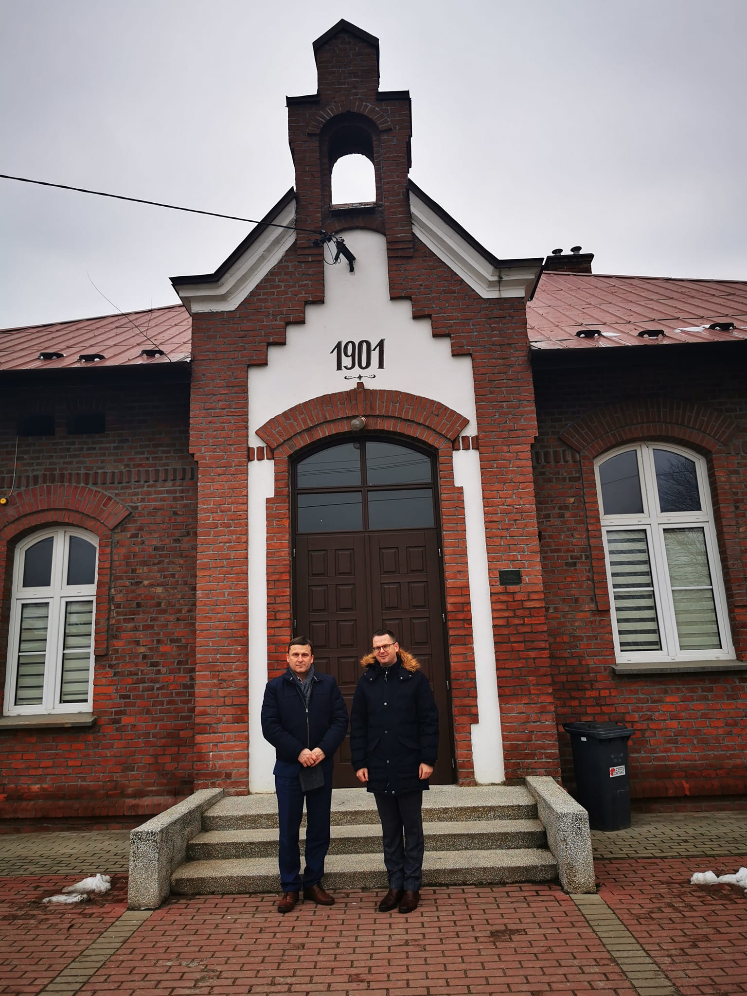 zdjęcie przedstawia od lewej Wojciech Skruch i Tomasz Banek, w tle budynek Domu Ludowego w Demblinie