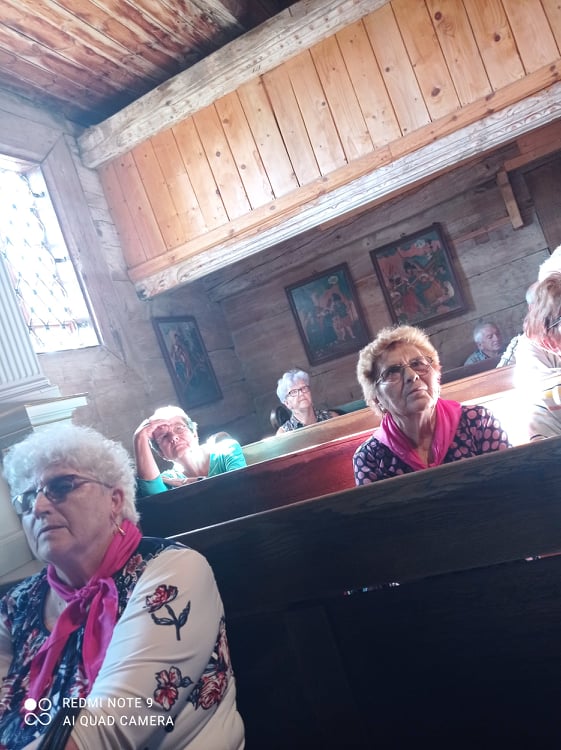 Seniorzy siedzący w ławkach w kaplicy 