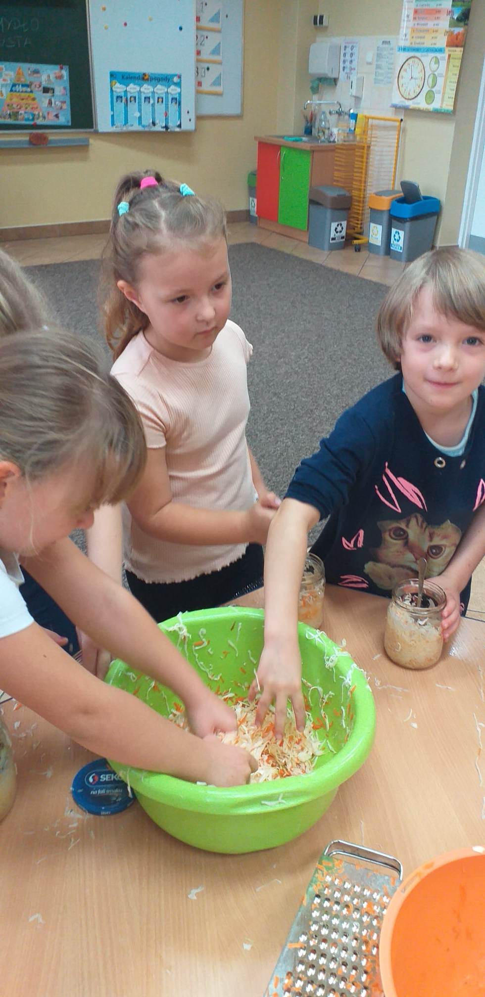 Dzieci wyjmują rękoma kapustę z zielonej miski