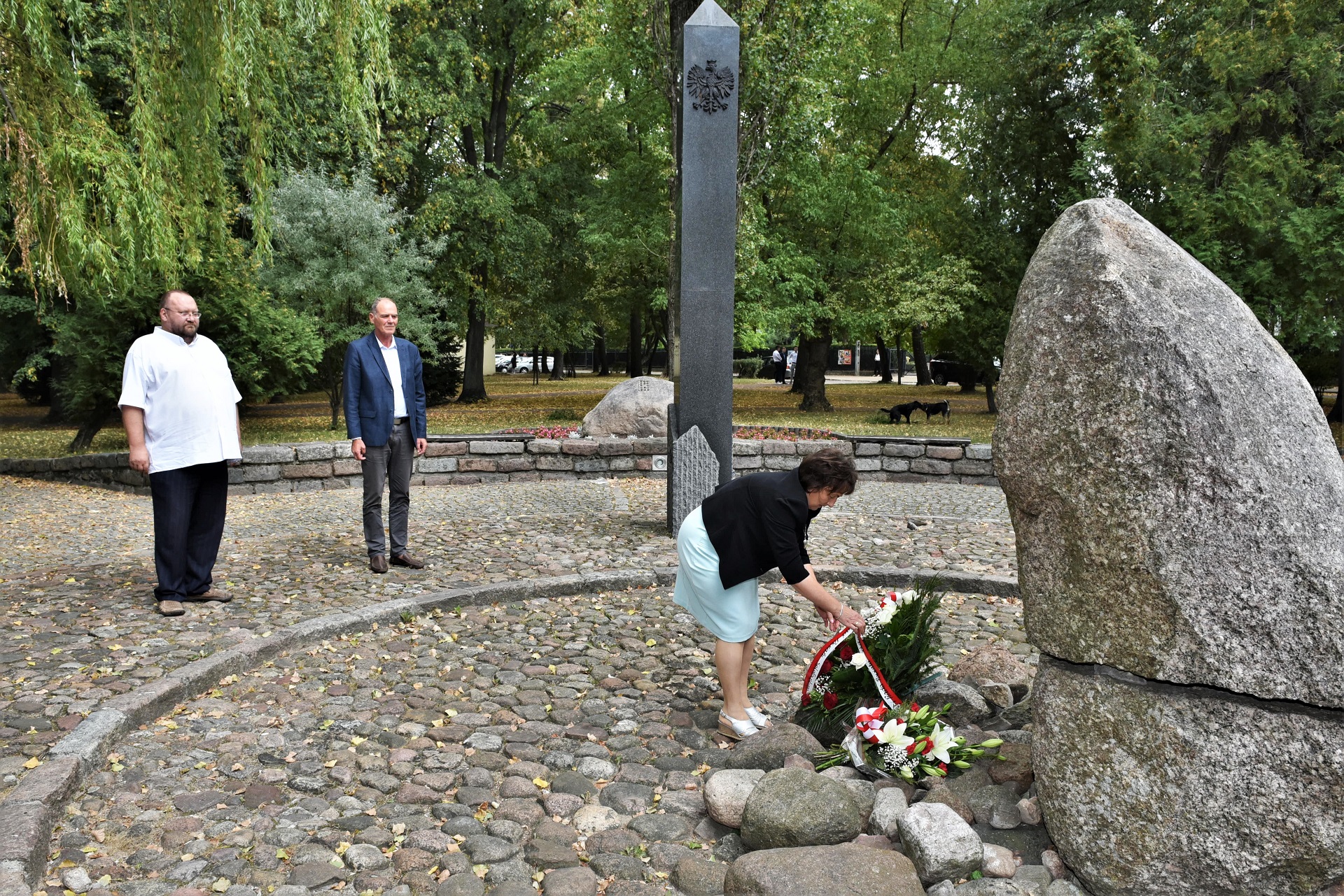 Starosta Elżbieta Sadowska składa kwiaty w centralnej części pomnika Czynu Niepodległościowego w Sokołowie Podlaskim. W tle przewodniczący Rady Powiatu Sokołowskiego oraz wicestarosta Ryszard Domański.