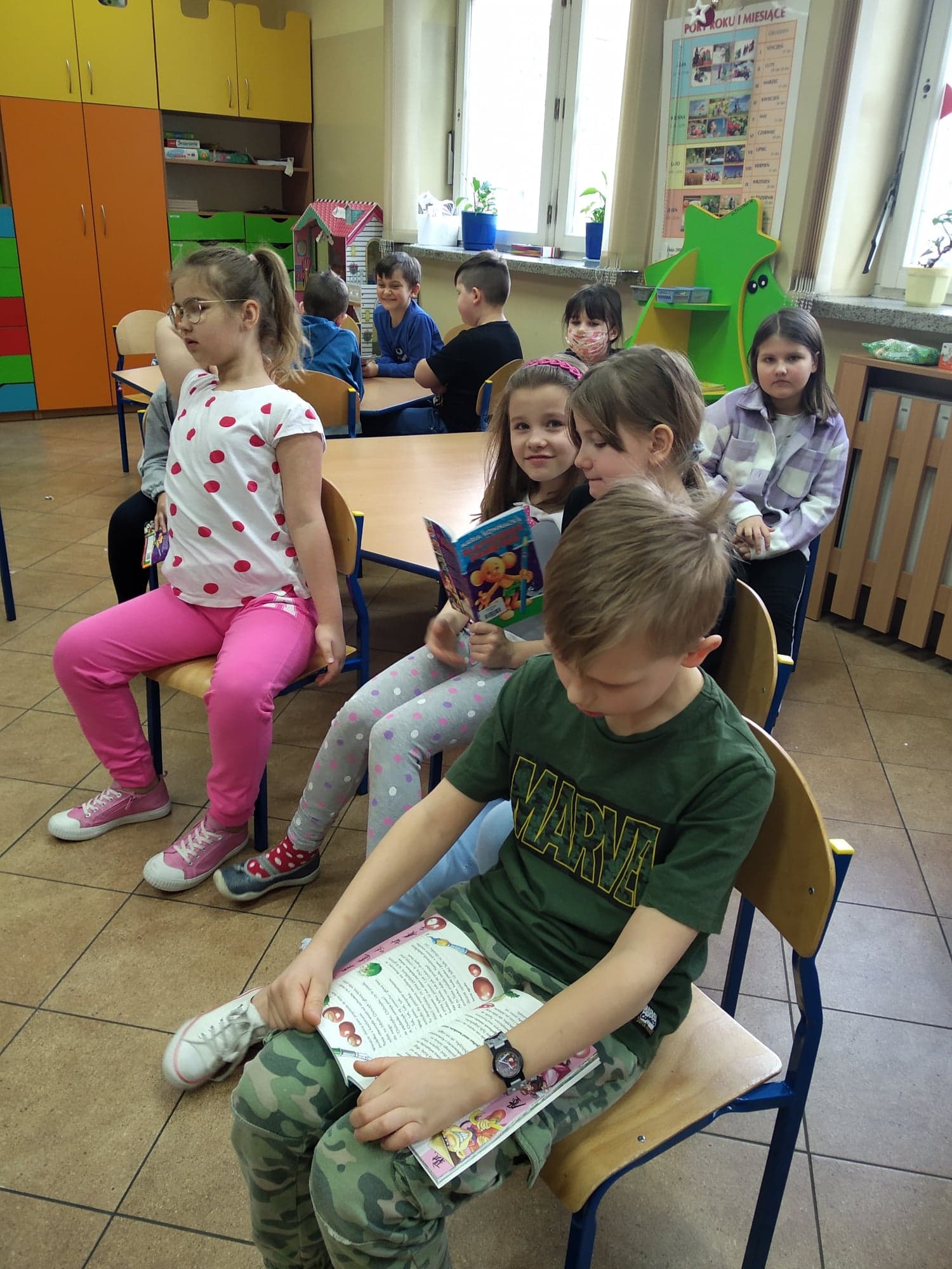 Dzieci siedzące na krzesłach i czytające książki
