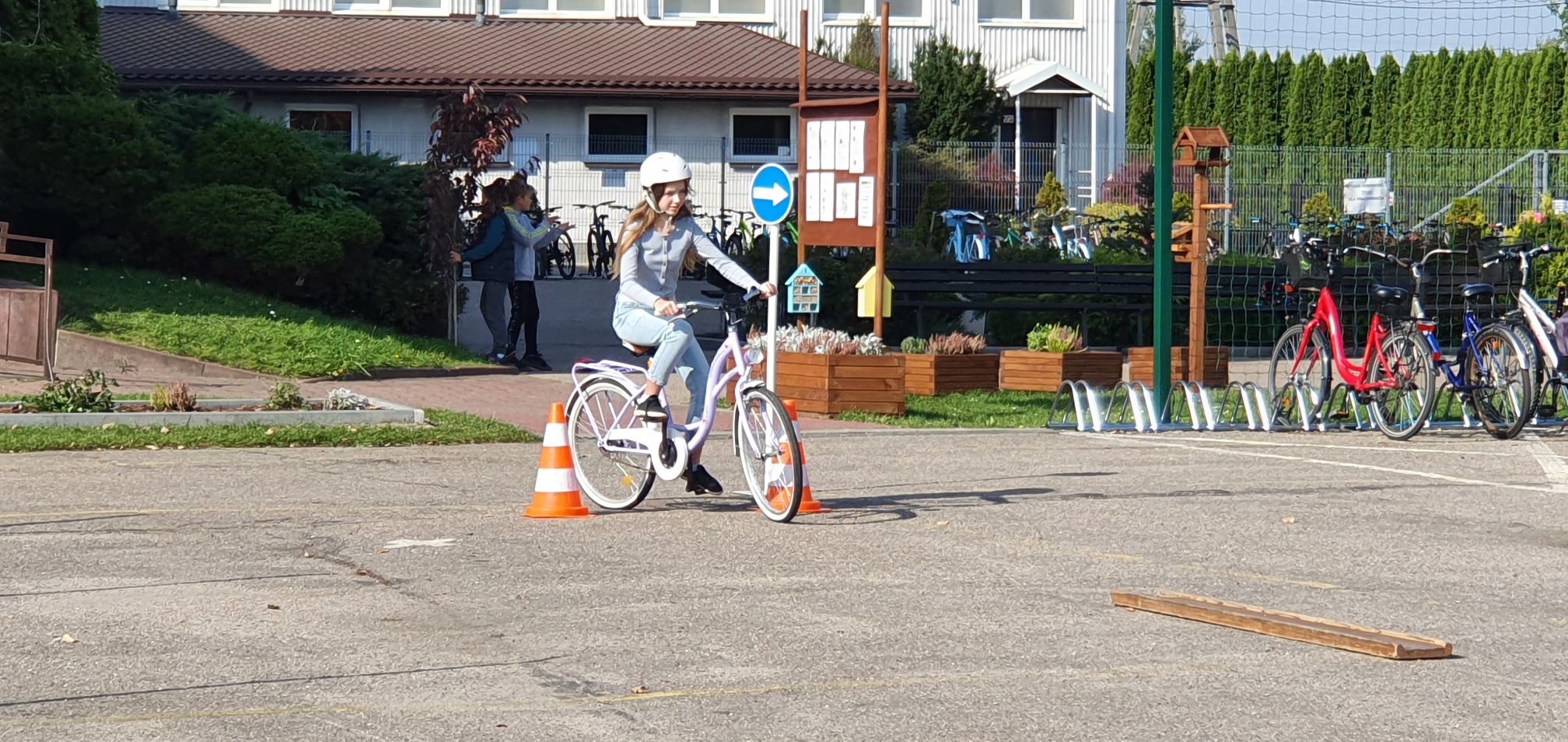 Dziewczynka jedzie rowerem po placu pachołki