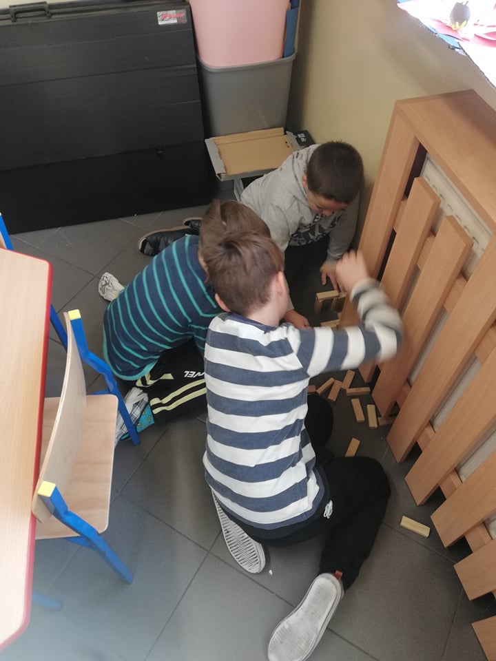 Dzieci układają wieżę z drewnianych klocków