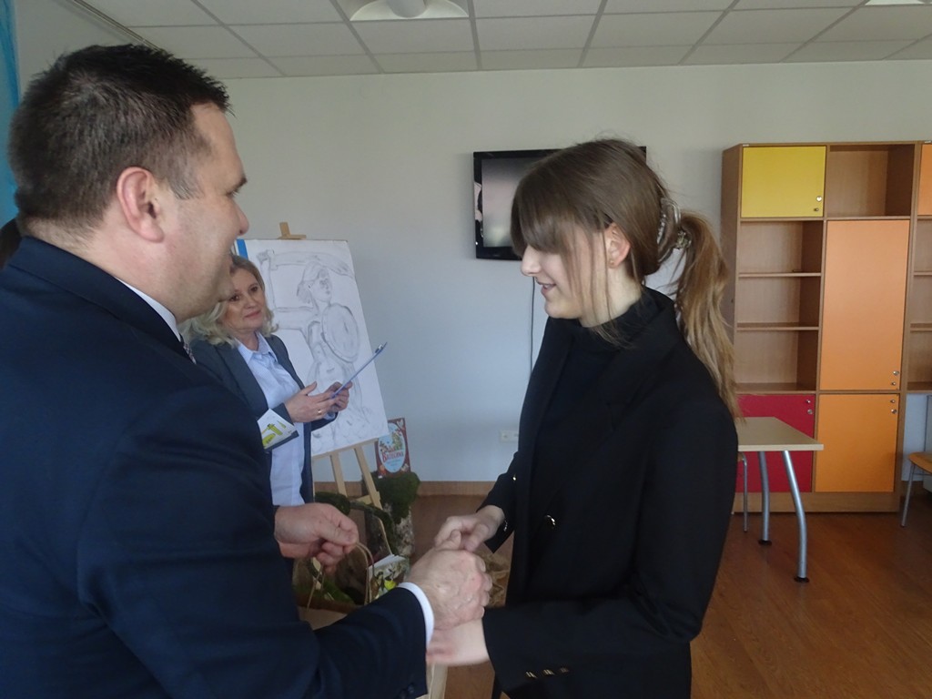Zdjęcie przedstawia wójta Gminy Somianka wręczającego nagrodę za zajęcie miejsca uczestniczce gminnych eliminacji konkursu recytatorskiego „Warszawska Syrenka”.