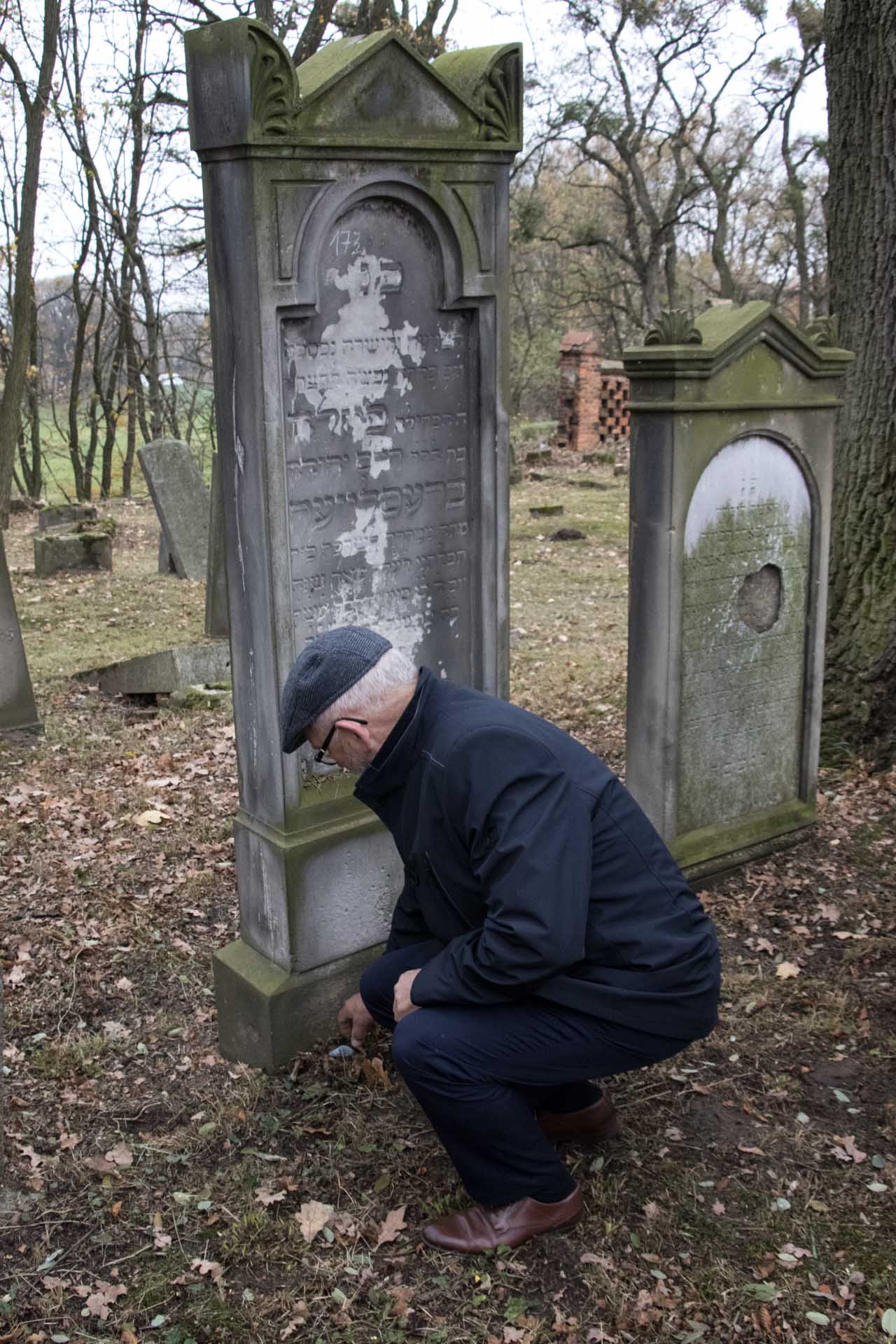 Złożenie kamyków na grobach na cmentarzu żydowskim w Oleśnie - na zdjęciu Wicestarosta Stanisław Belka