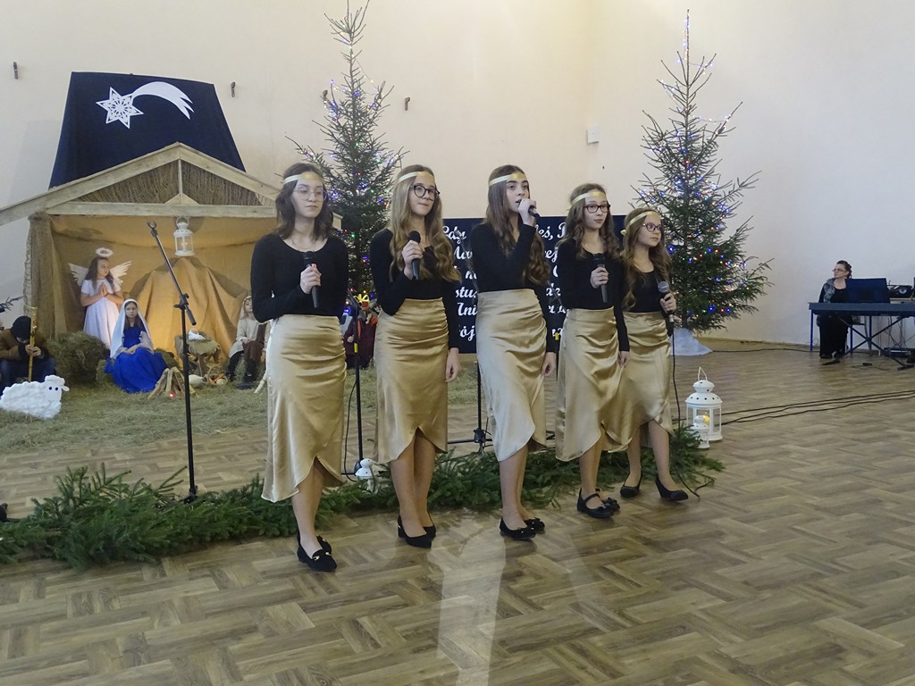 Zdjęcie przedstawia zespołowy występ pięciu dziewcząt. Ubrane są w tę same stroję, w których dominuje kolor czarny oraz złoty. 