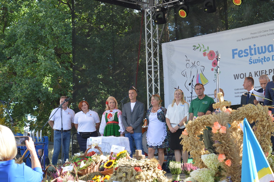 Zdjęcie przedstawia widok na scenę oraz uczestników i gospodarzy festiwalu. 