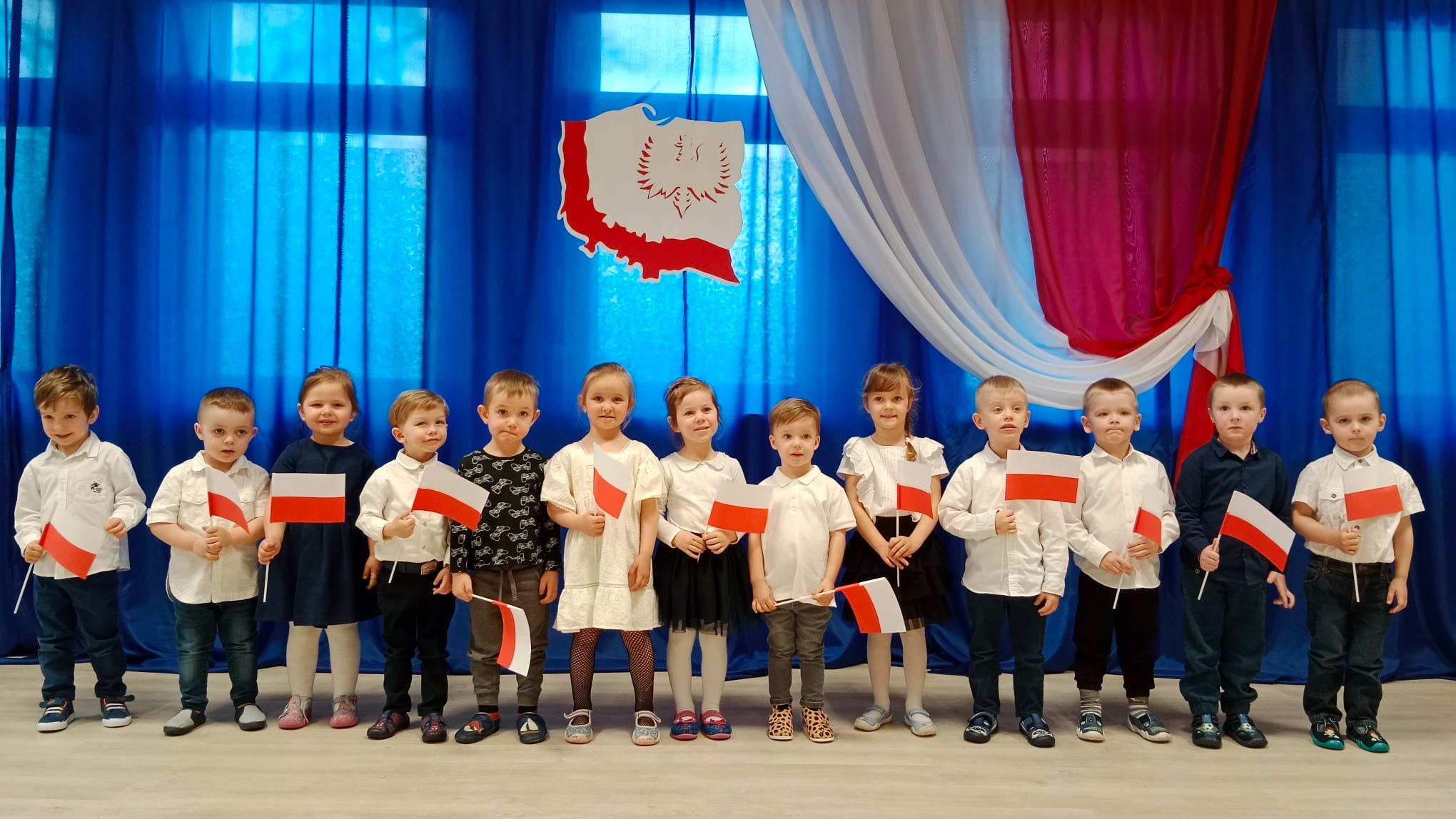 Dzieci w strojach galowych z flagami Polski