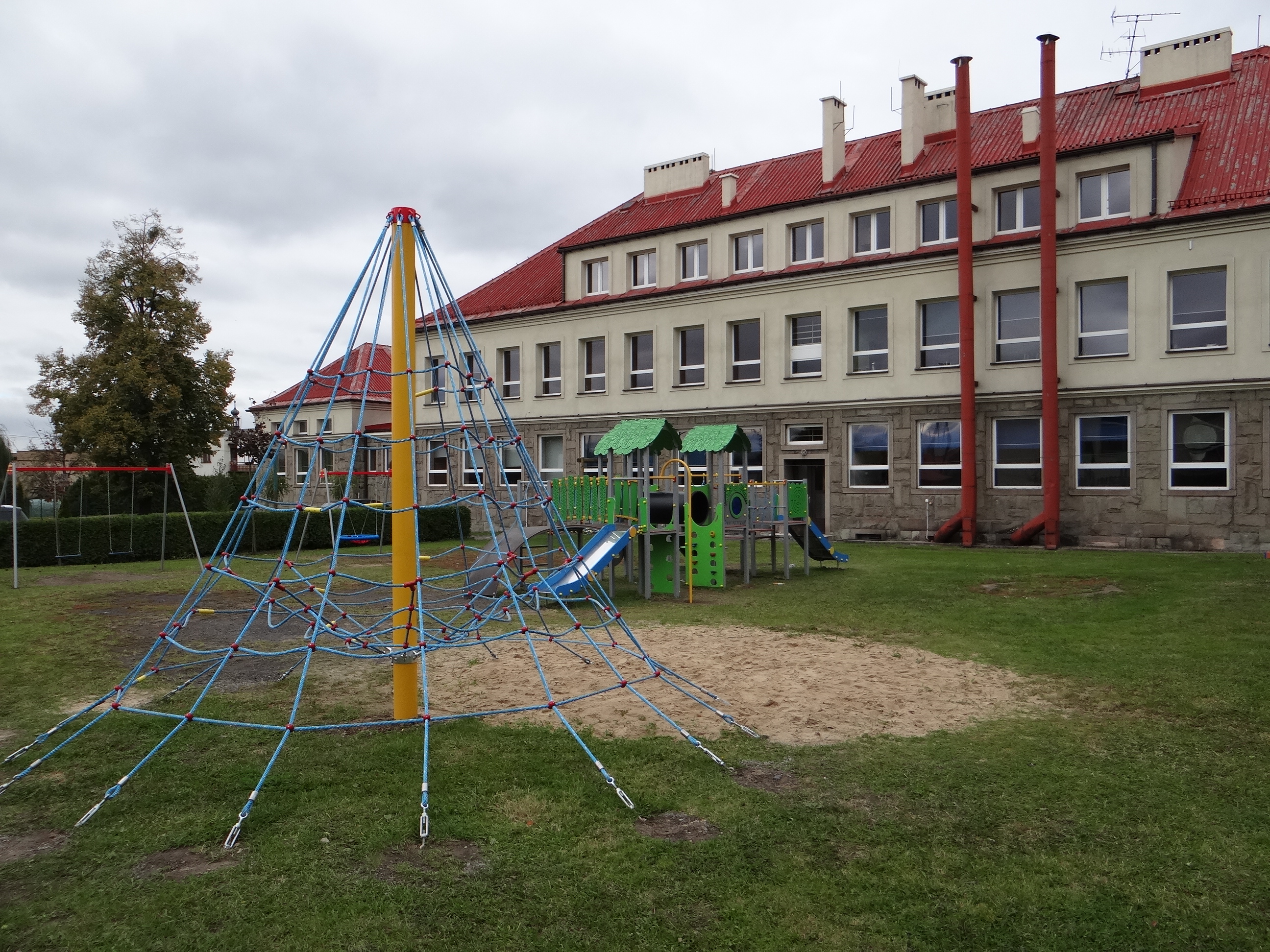 
Ogólnodostępny plac zabaw przy Szkole Podstawowej w Pogwizdowie po modernizacji (3). Widoczna część urządzeń placu. Z tyłu budynek szkolny (skrzydło północne).
