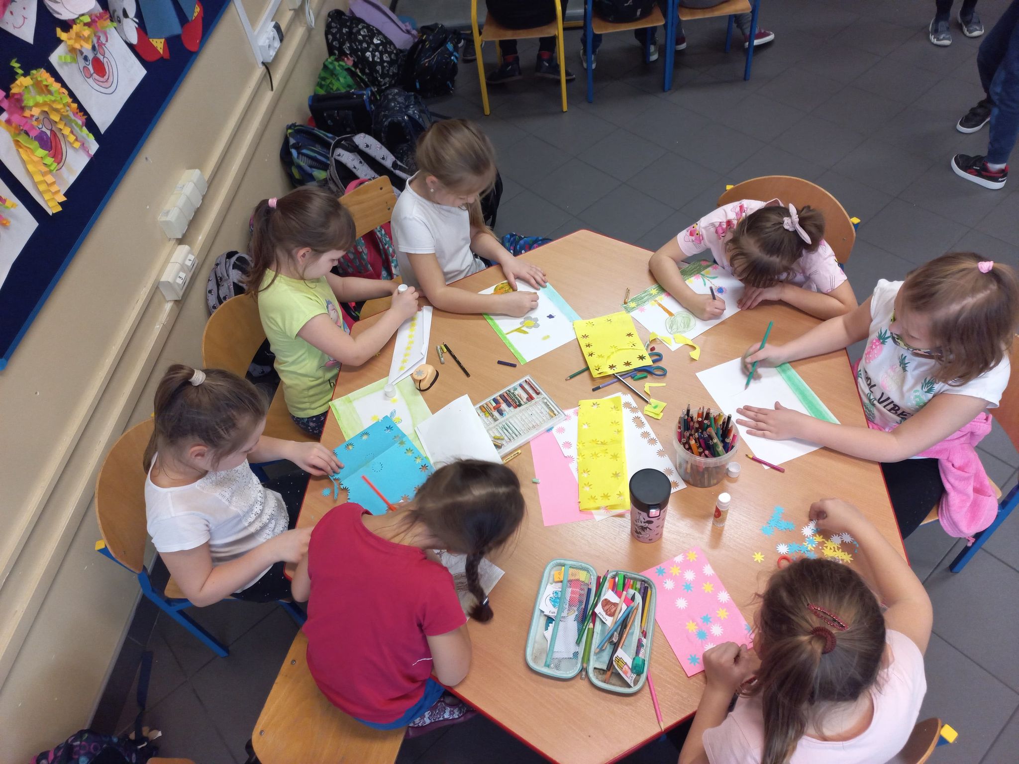 Dzieci siedzą przy stoliku i malują obrazki