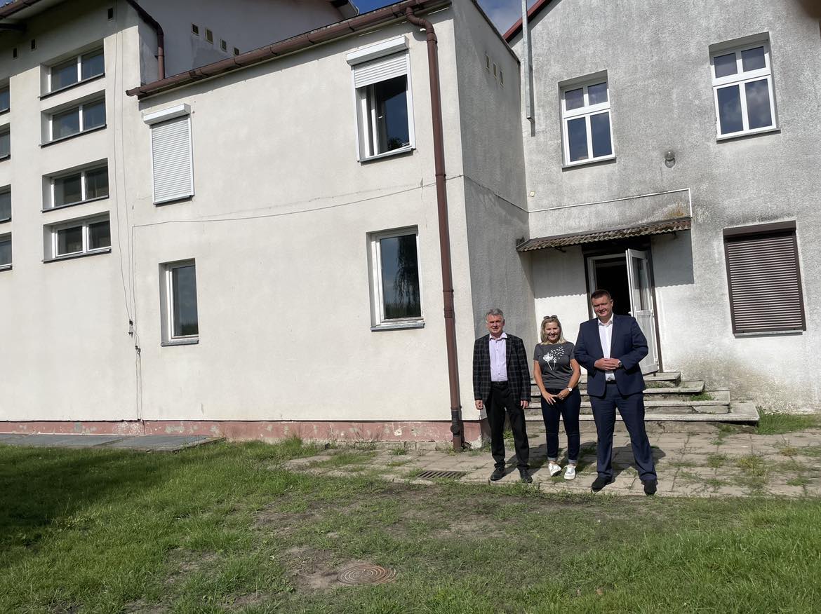 Poseł Porzucek, Burmistrz Janusz Piechocki i kobieta stoją przed budynkiem szkoły podstawowej w Lipinach.