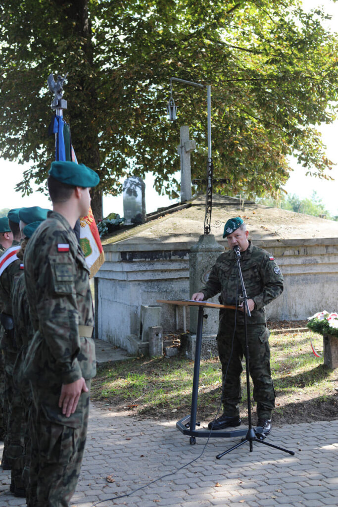 Mężczyzna w wojskowym ubraniu podczas przemówienia na cmentarzu w Brańszczyku.