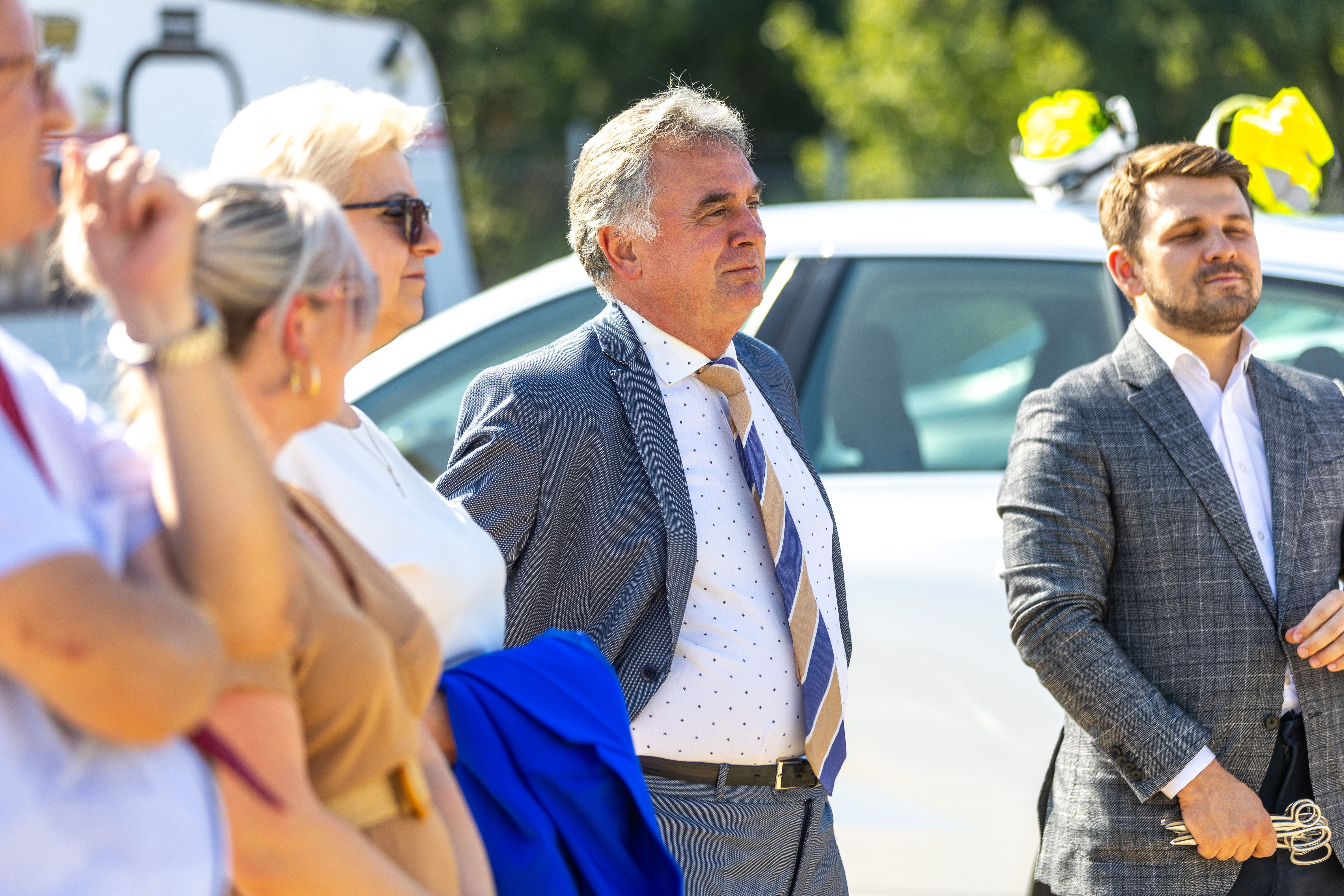 Burmistrz Margonina Janusz Piechocki wśród 4 innych osób stojących przed białym samochodem