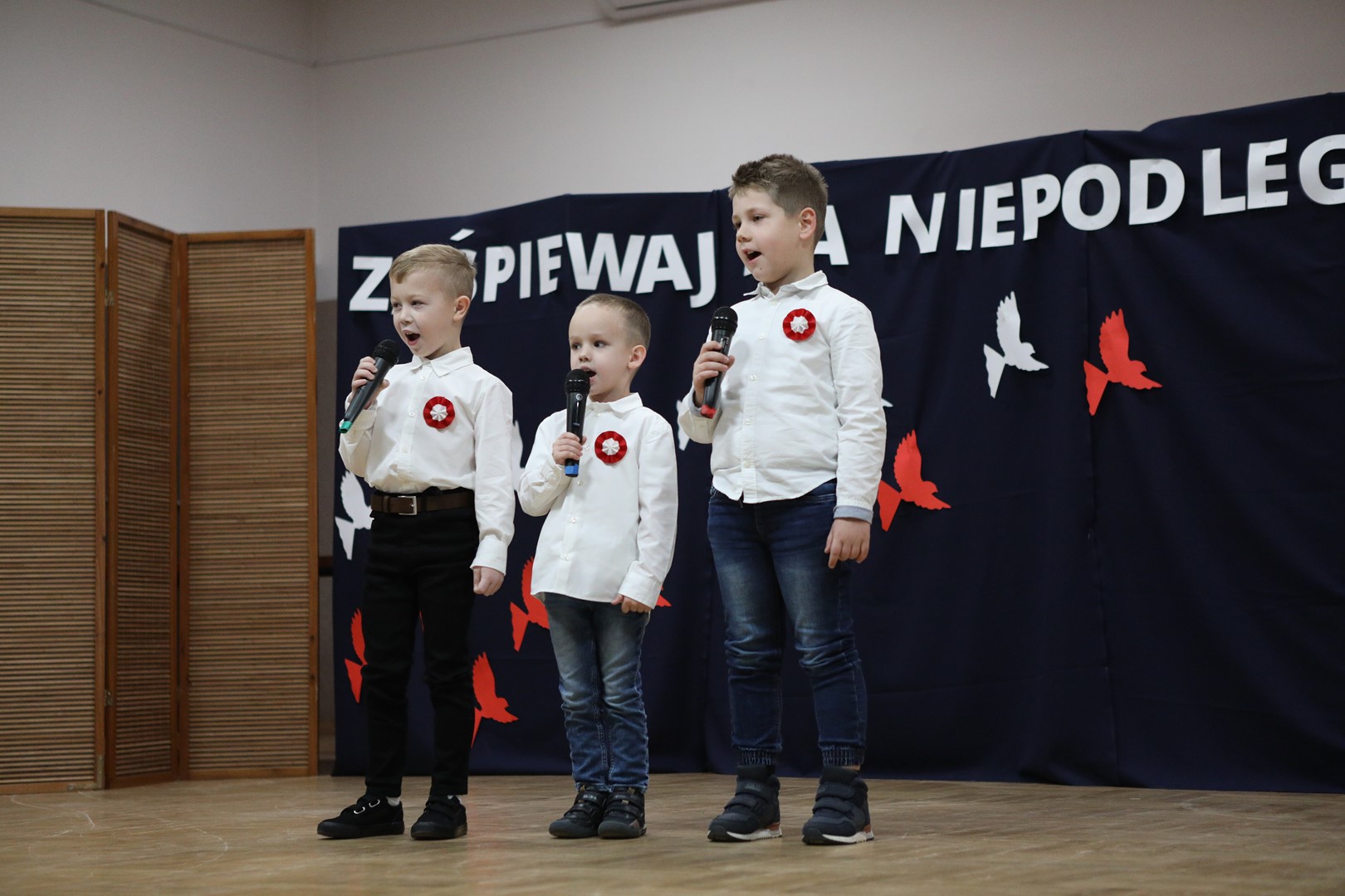 Uczestnicy konkursu podczas występu wokalnego - trzech chłopców.