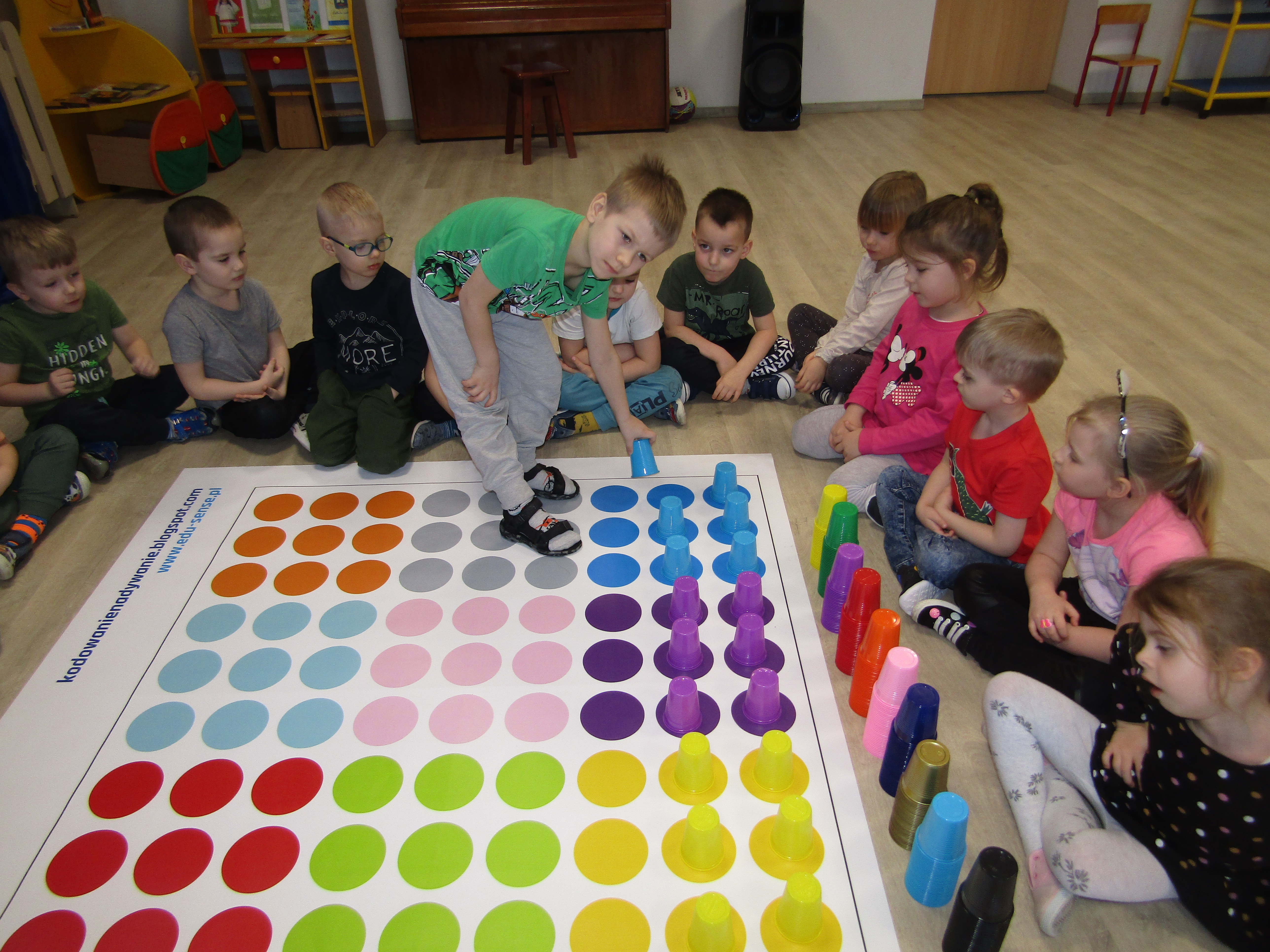 Dzieci ustawiają kolorowe kubeczki na polach w tym samym kolorze