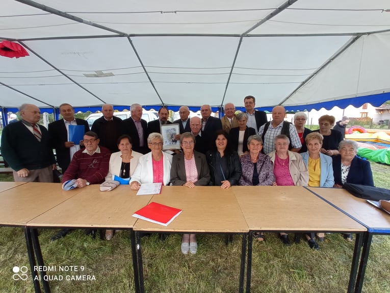 Seniorzy Klubów Seniora pozują pod namiotem na uroczystościach z okazji memoriału Płk. Władysława Kabata