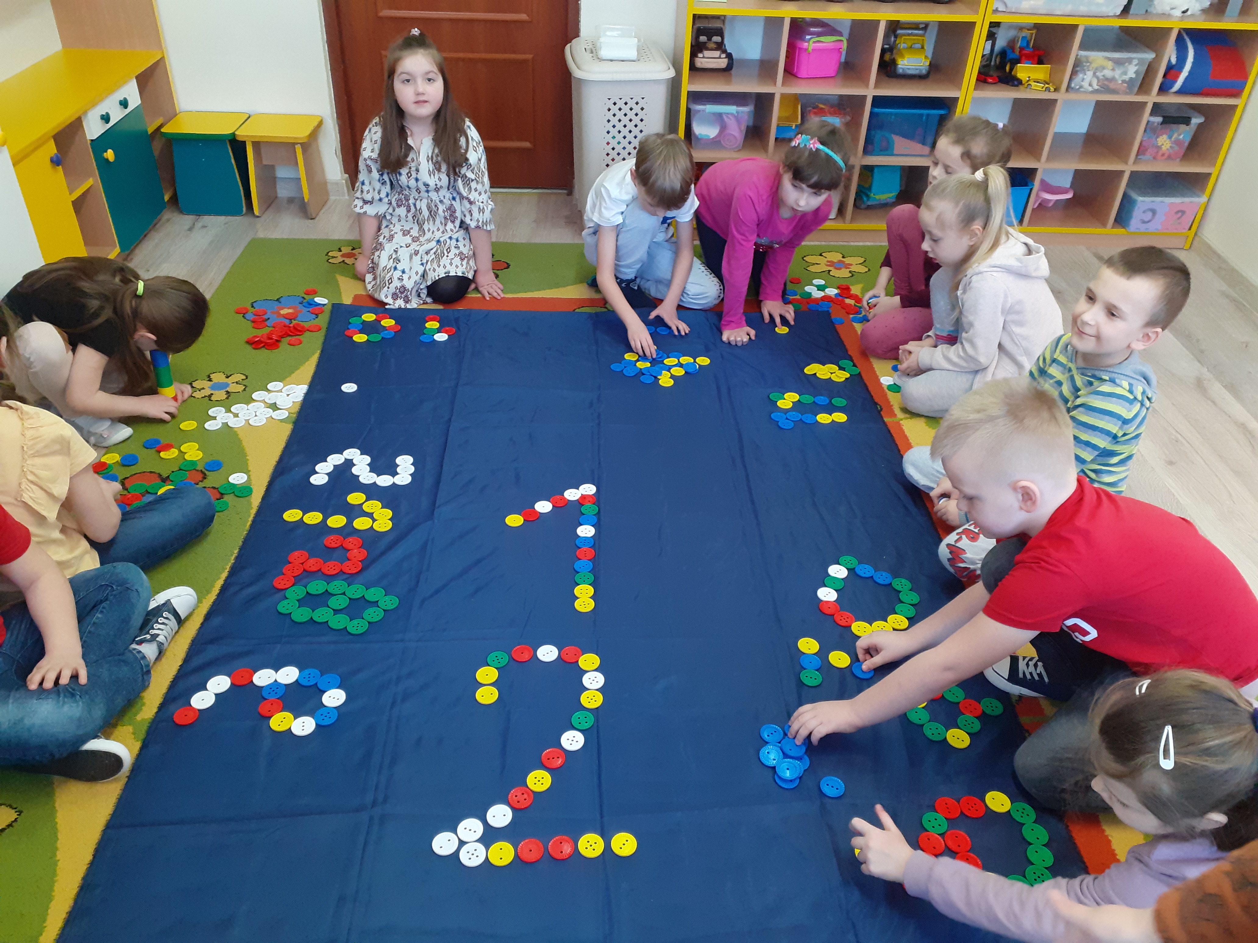 Dzieci układają cyfry z kolorowych guzików 