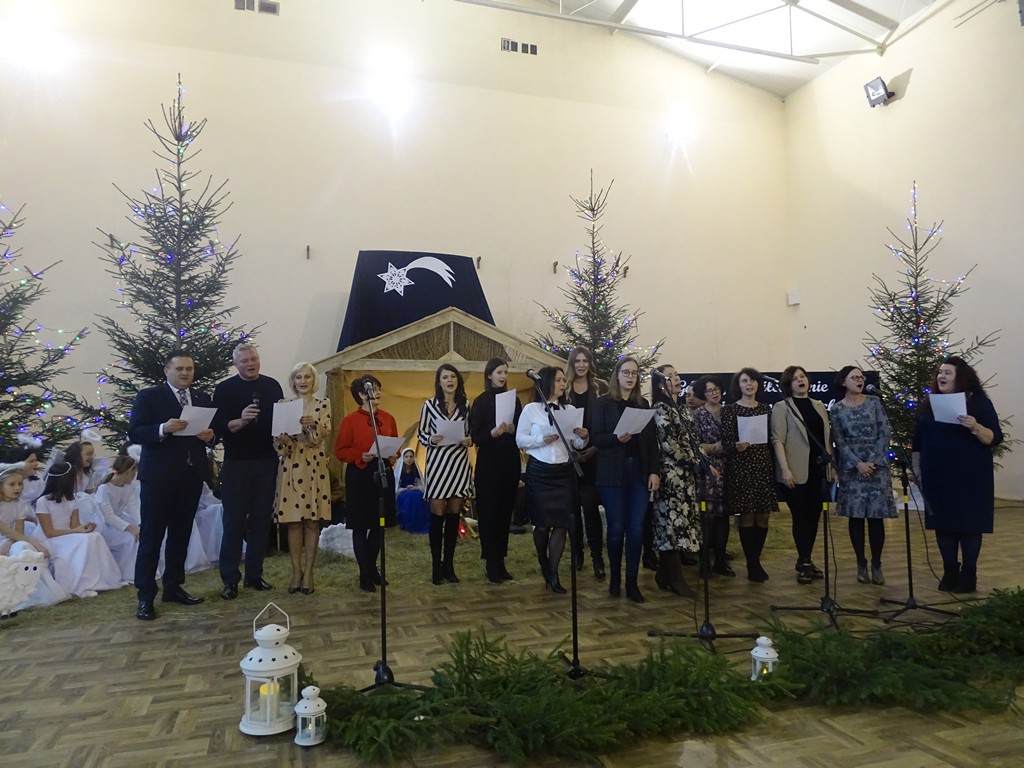 Zdjęcie przedstawia występ nauczycieli, dyrektorów, organizatora, a nawet samego pana Wójta Andrzeja Żołyńskiego, którzy również wzięli udział odśpiewując jeden utwór w Gminnym Przeglądzie Kolęd i Pastorałek.
