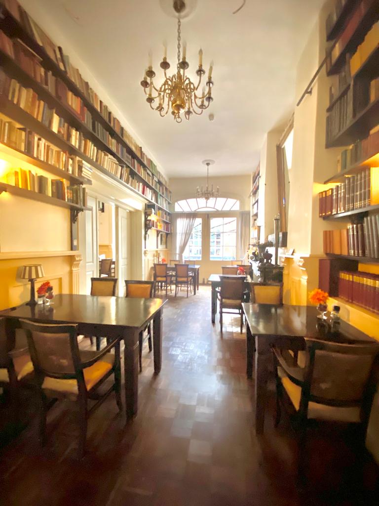 salę kawiarnianą. Wzdłuż ścian rozłożone są stoliki 4-osobowe oraz krzesła. Powyżej na ścianie wiszą półki z książkami.
