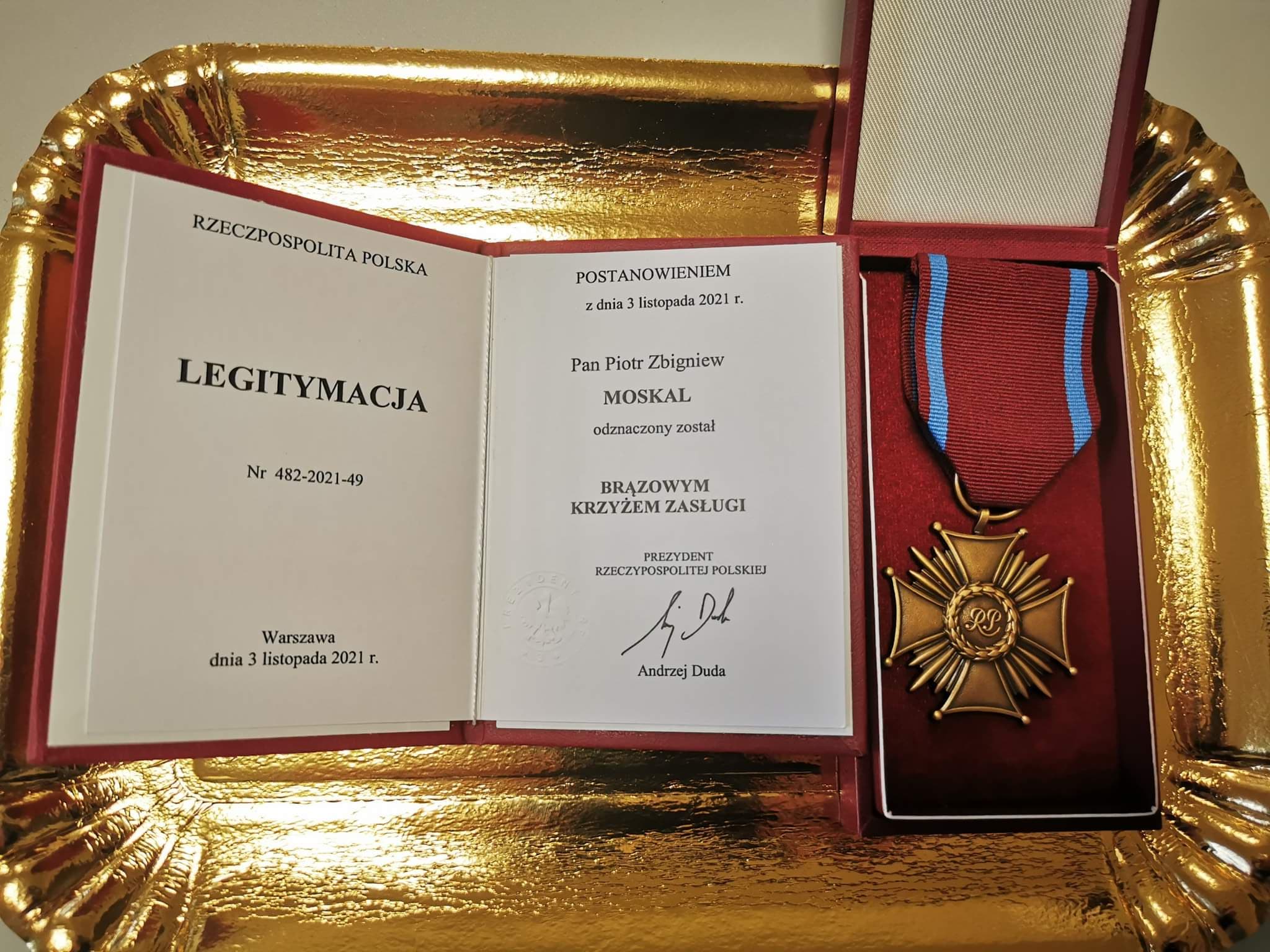 Zdjęcie przedstawia na złotej tacy położony w etui medal oraz legitymację