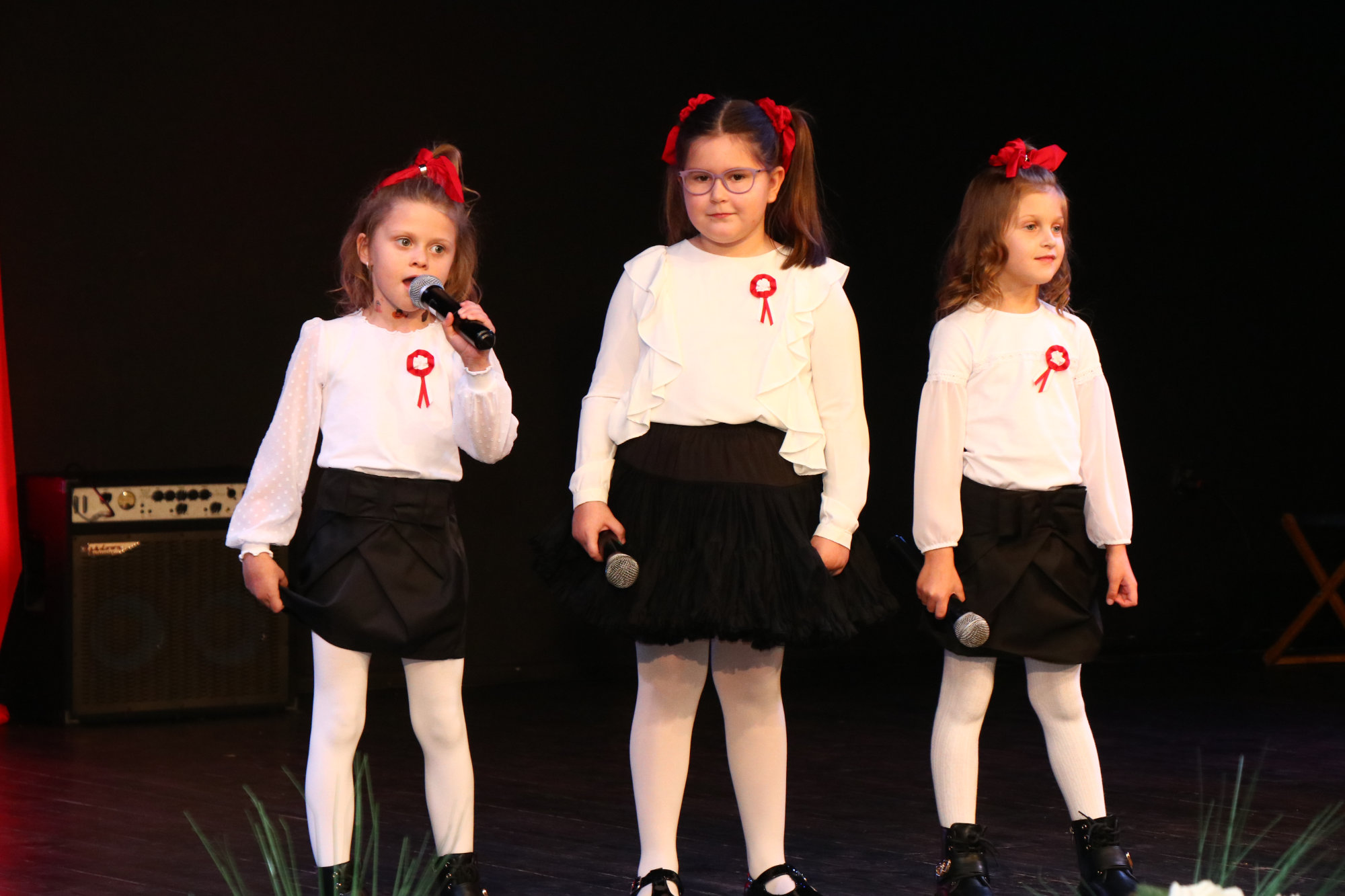 Trzy dziewczynki śpiewające podczas koncertu z okazji Święta Niepodległości
