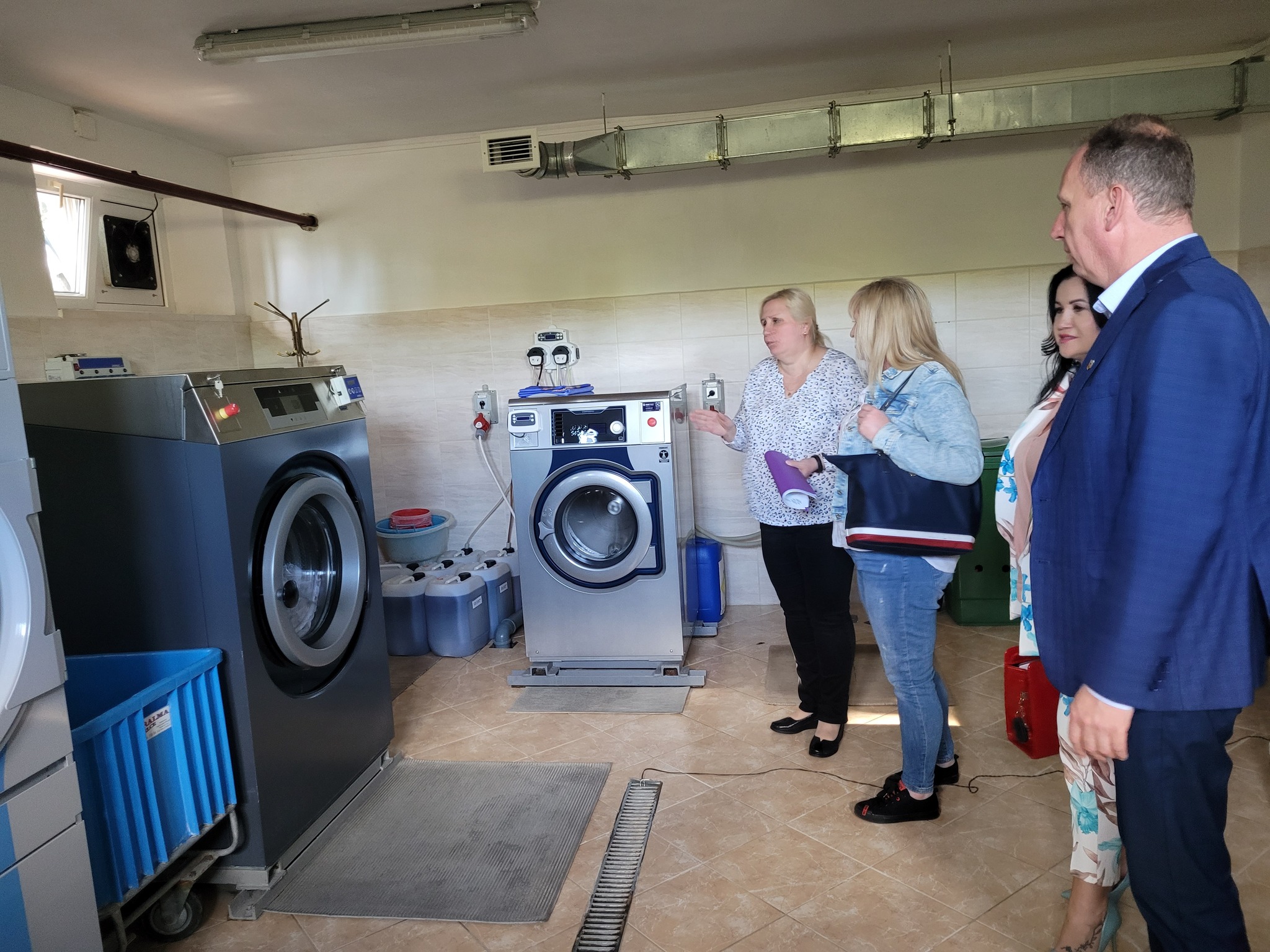 Radni oglądają wnętrze DPS - pralnia z nowymi urządzeniami
