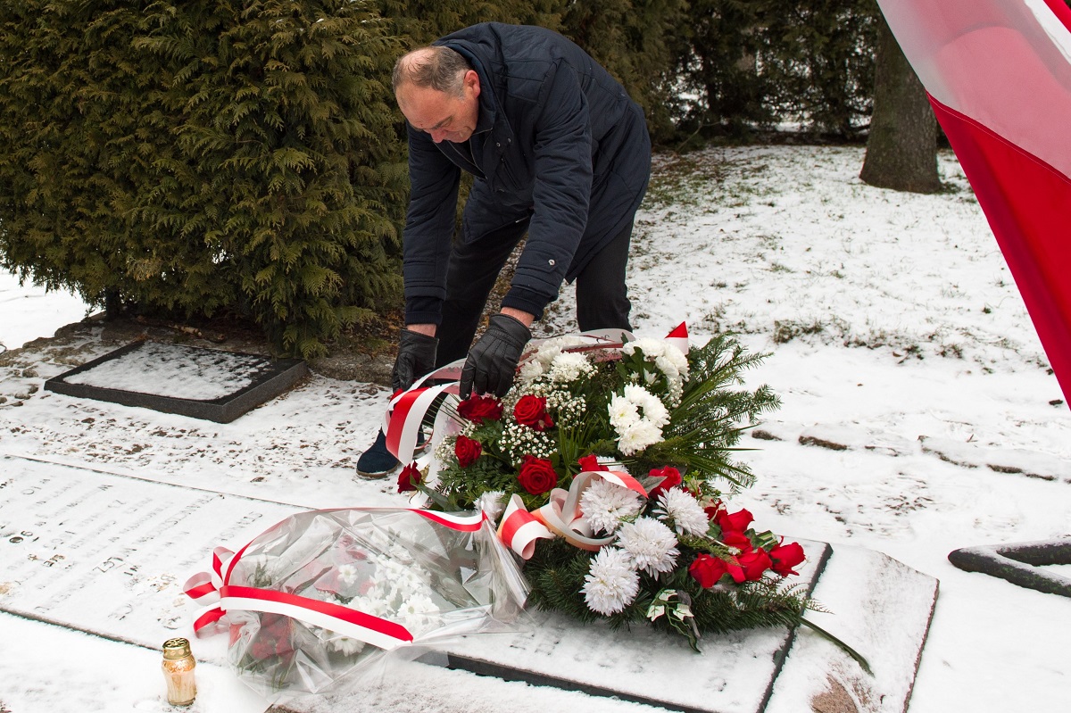 Wicestarosta Ryszard Domański układa wiązankę z biało - czerwonych kwiatów na zielonym podkładzie na płytach znajdujących się przed pomnikiem ks. Brzóski w Sokołowie Podlaskim.